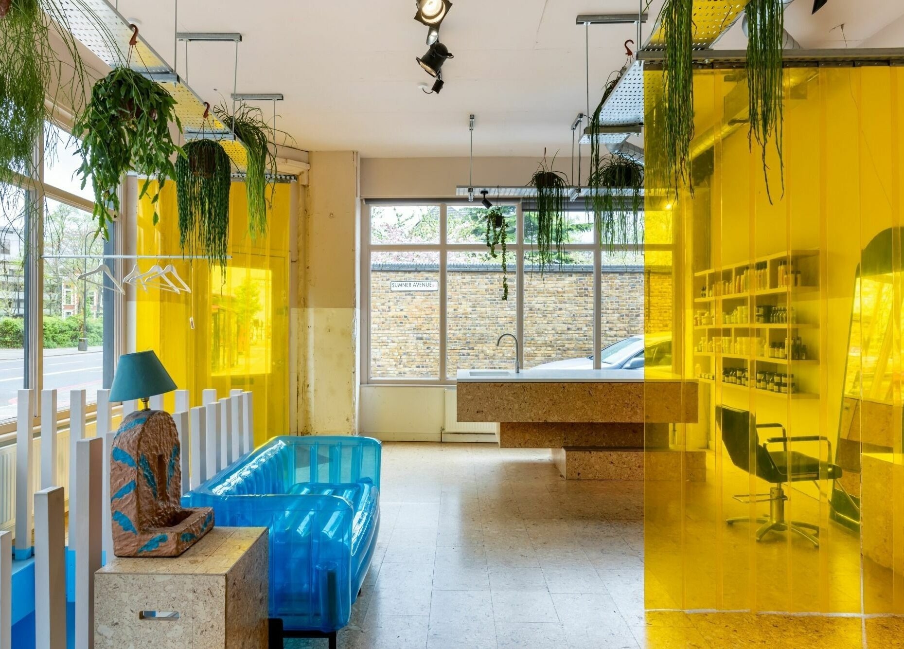 Bright interior of Crab Salad Peckham in London, GB with yellow dividers and greenery accentuating blue seating.