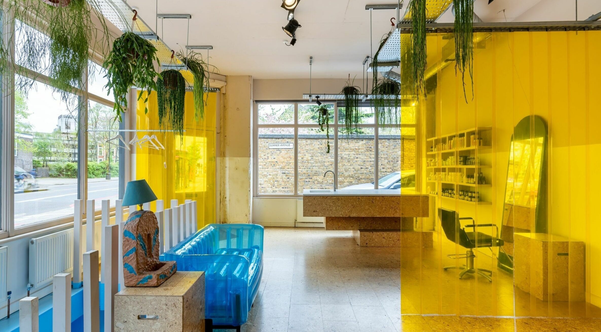 Bright interior of Crab Salad Peckham in London, GB with yellow dividers and greenery accentuating blue seating.