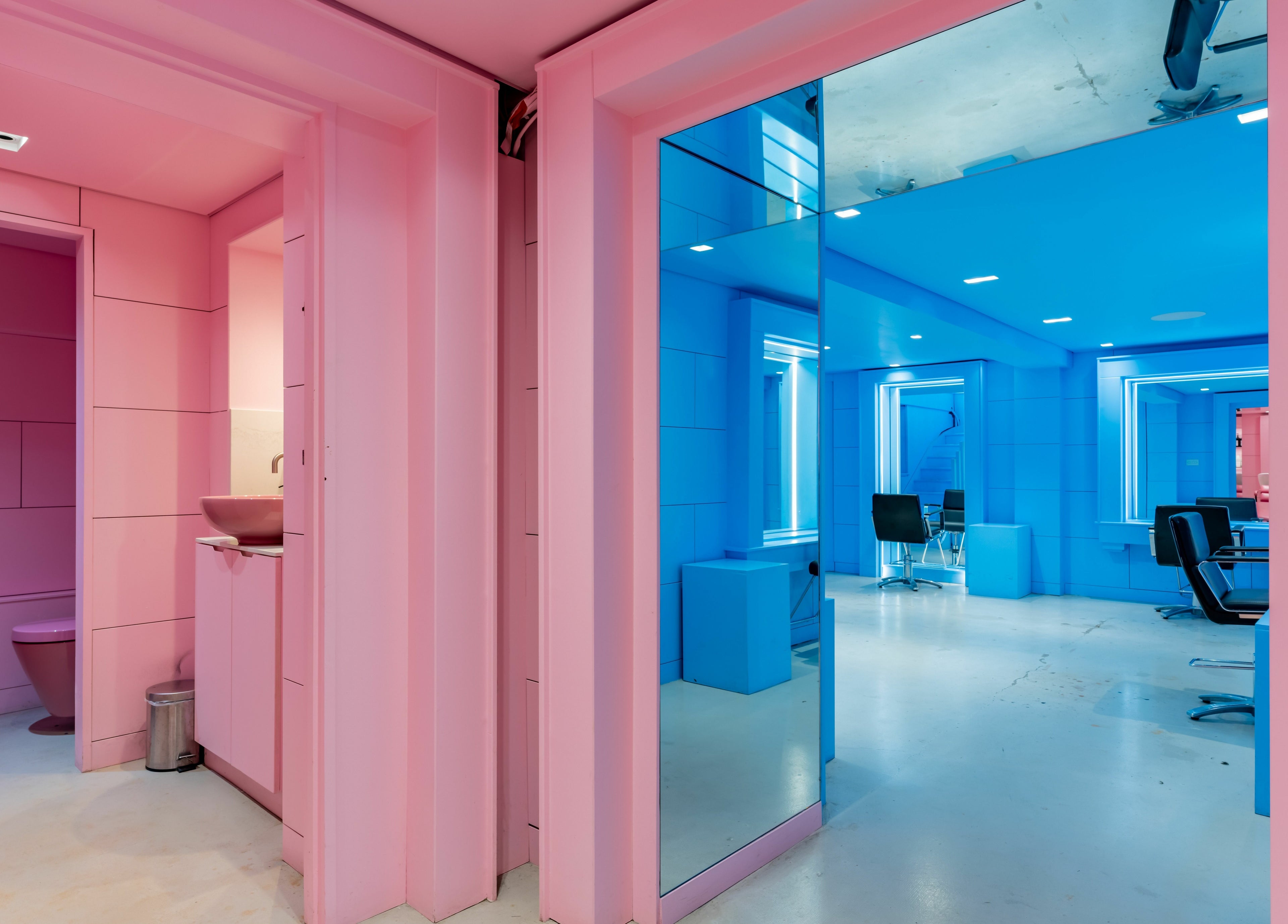 Vibrant pink and blue interior of Crab Salad Peckham in London, GB, featuring modern salon chairs.