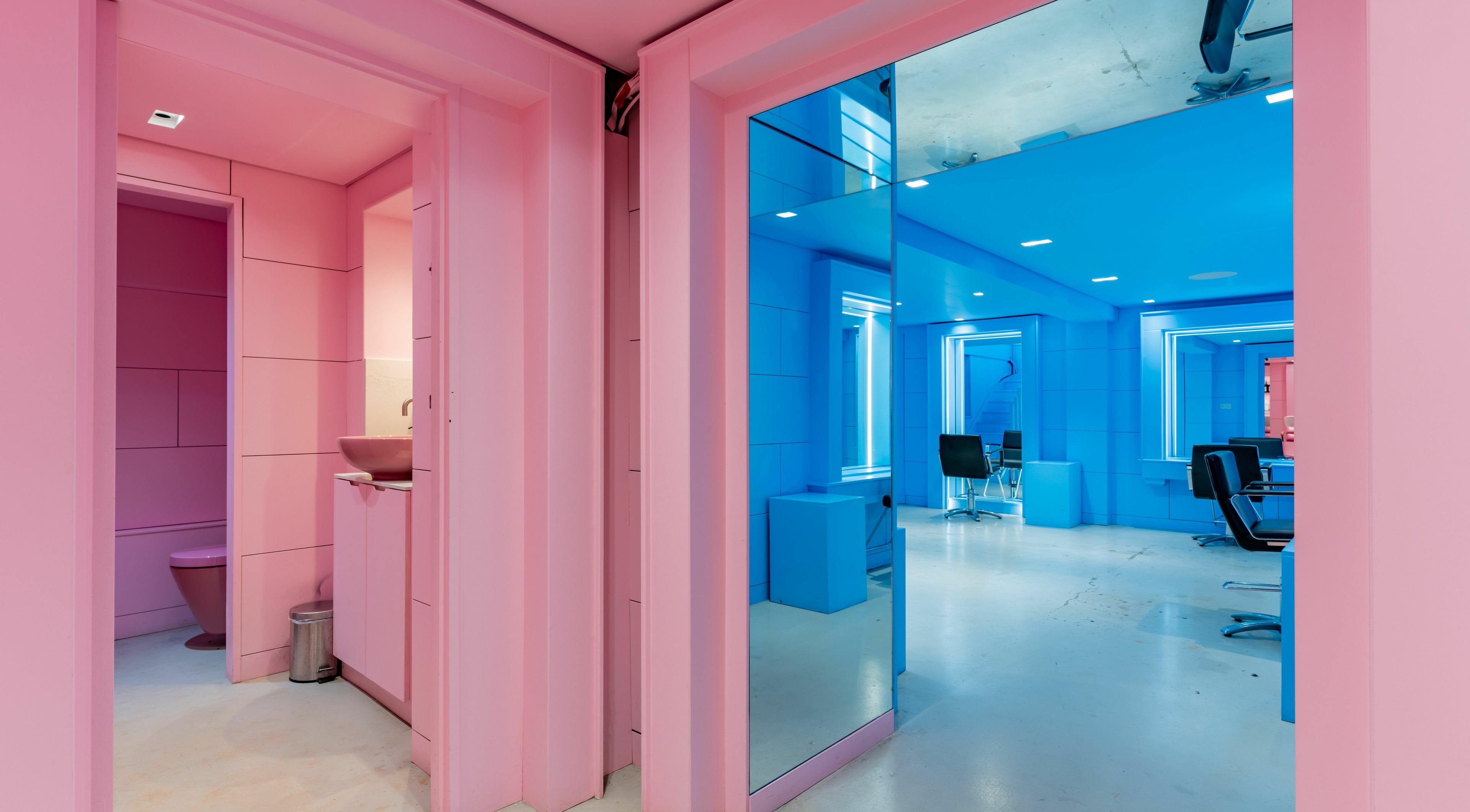 Vibrant pink and blue interior of Crab Salad Peckham in London, GB, featuring modern salon chairs.
