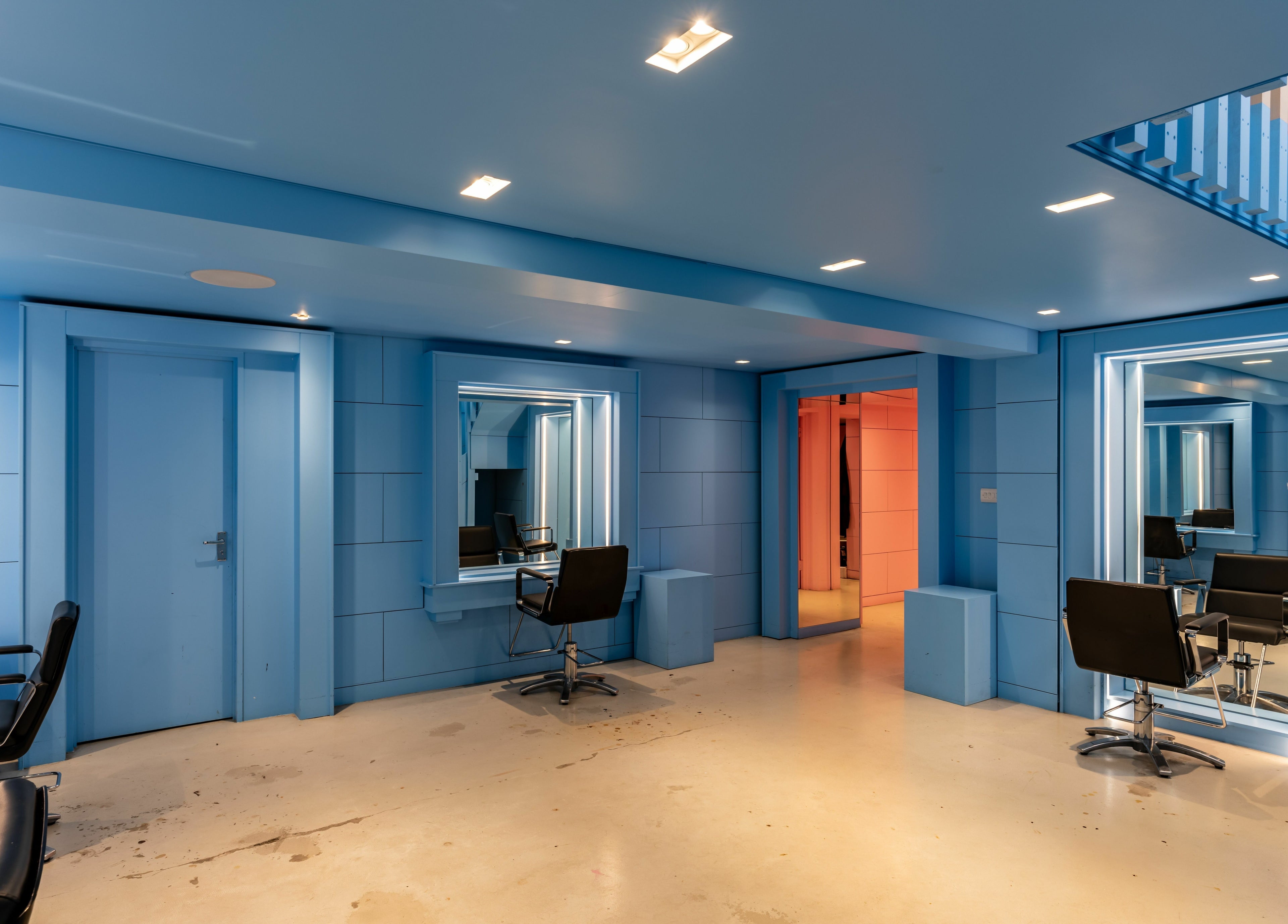 Modern blue interior of Crab Salad Peckham salon in London, GB, featuring sleek design and comfortable chairs.