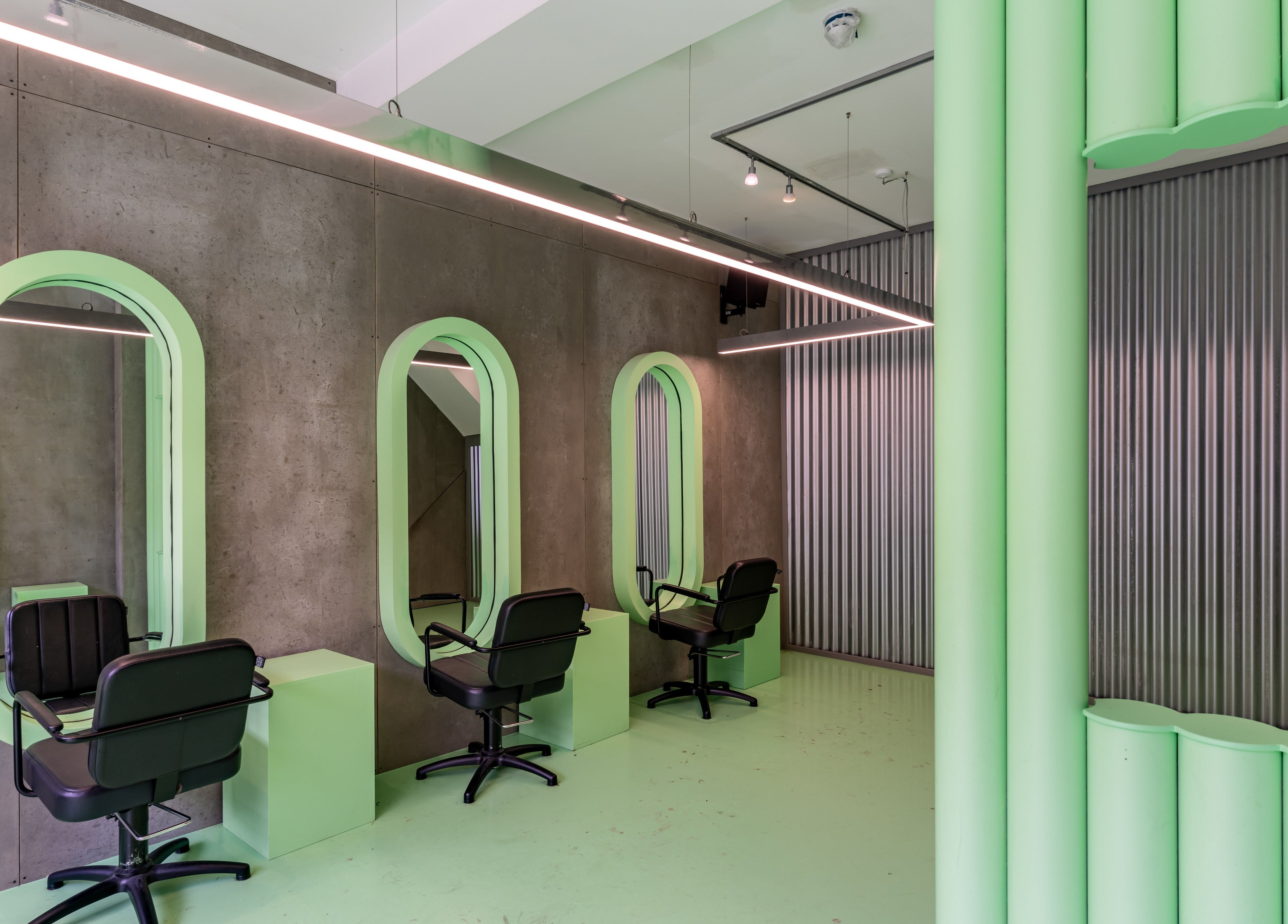 Modern salon interior with green accents at Crab Salad Highbury in London, GB features chic styling stations.