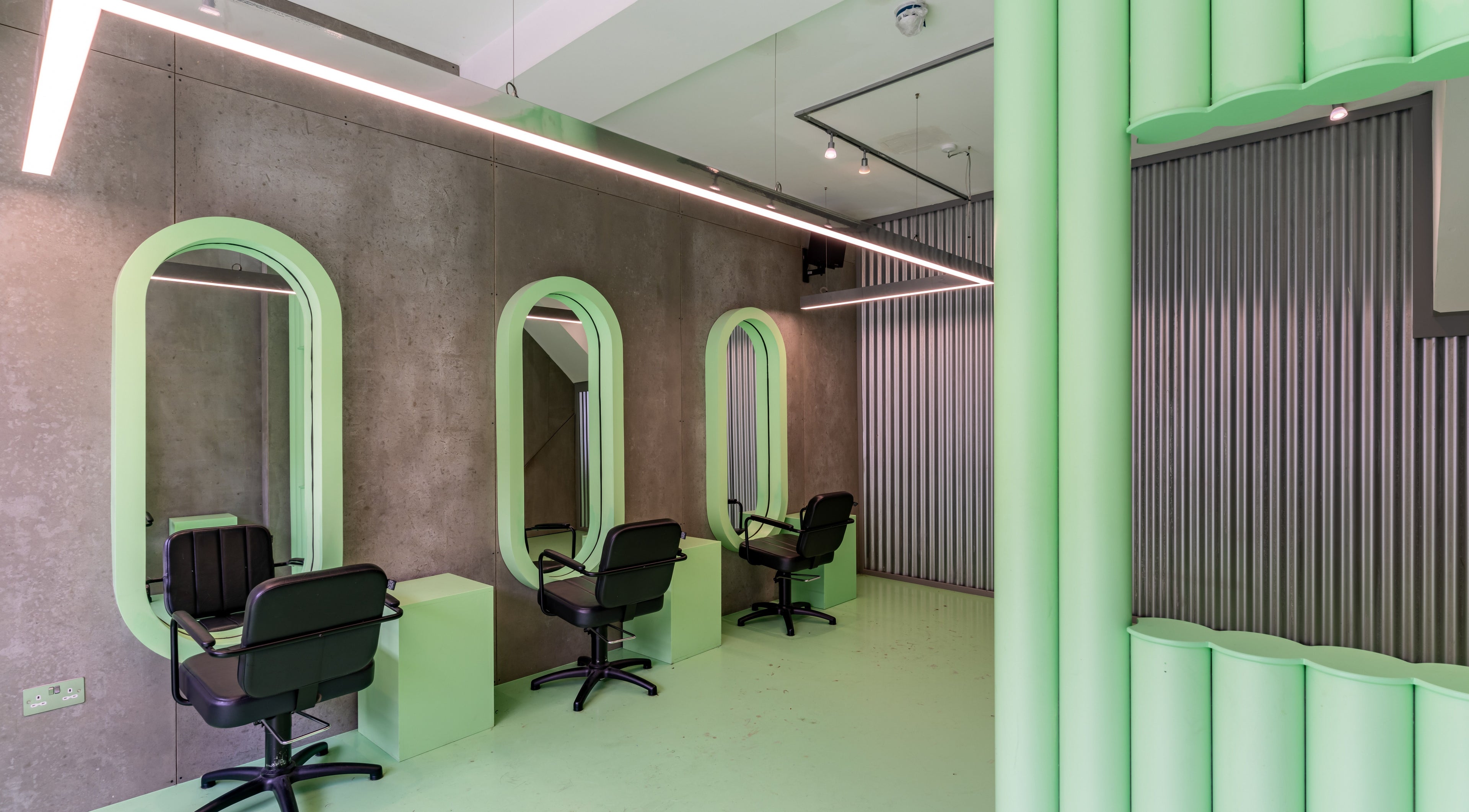 Modern salon interior with green accents at Crab Salad Highbury in London, GB features chic styling stations.