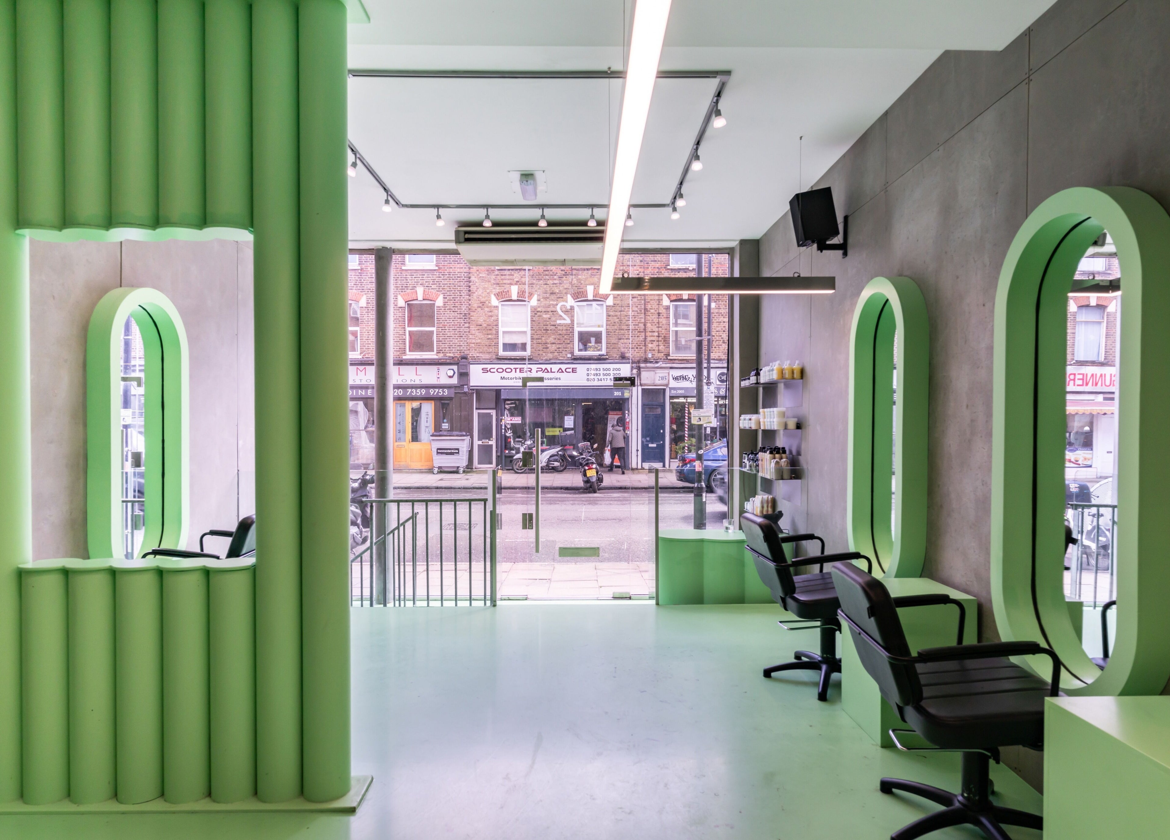 Bright, modern interior of Crab Salad Highbury salon in London, GB, featuring green decor and styling chairs.