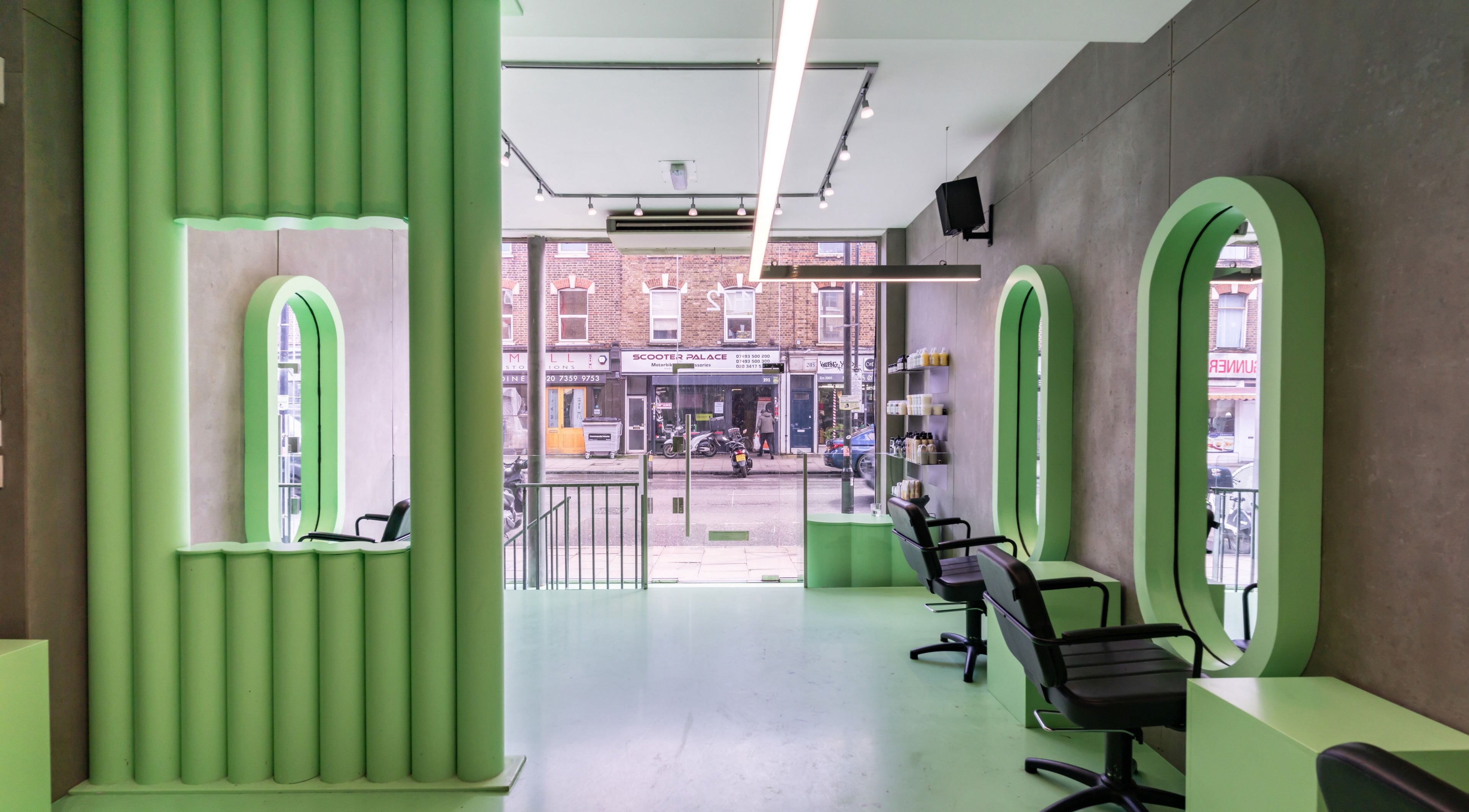 Bright, modern interior of Crab Salad Highbury salon in London, GB, featuring green decor and styling chairs.