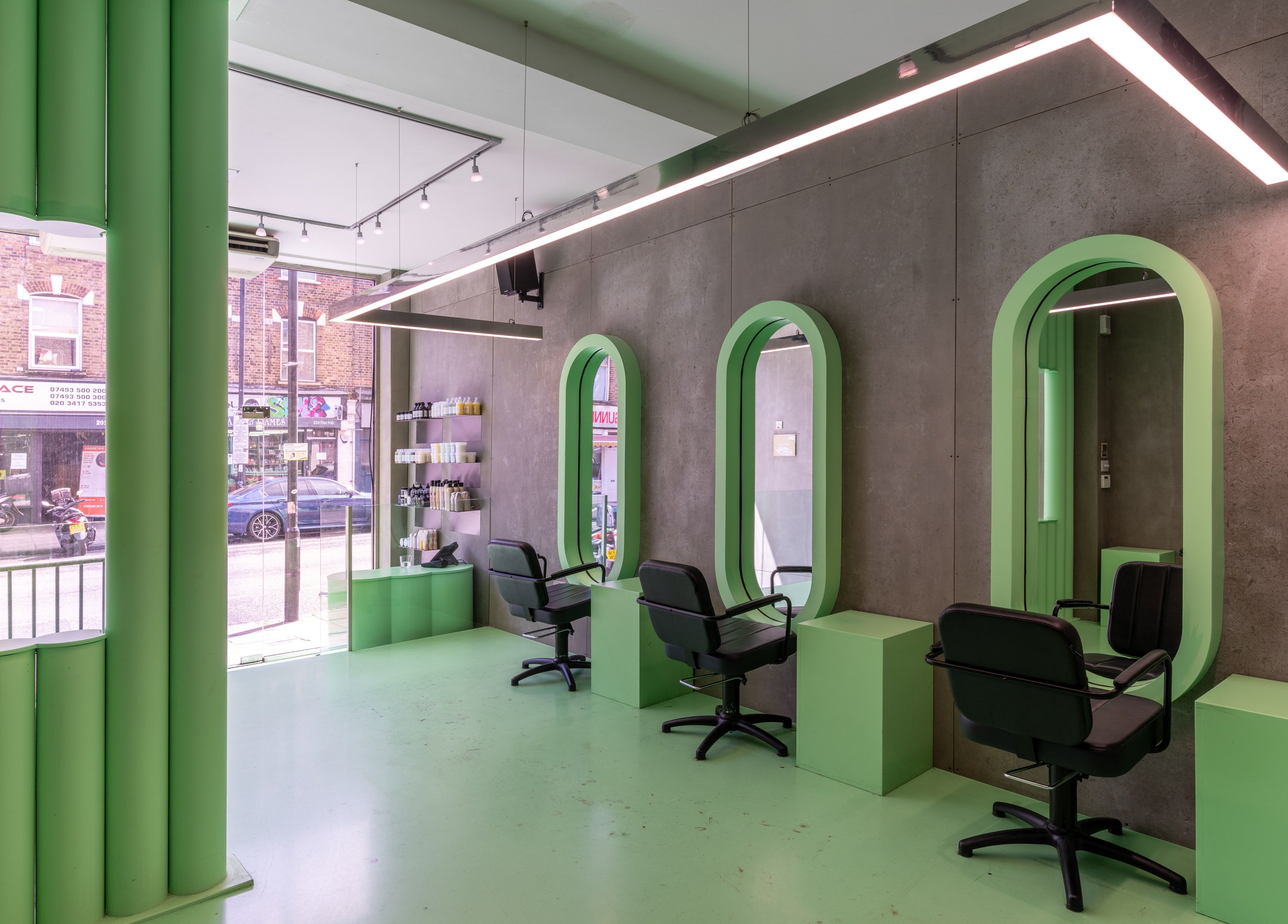 Modern salon interior at Crab Salad Highbury, London, GB with green decor and sleek styling stations.