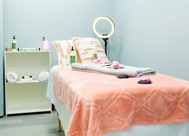 Relaxing massage room at Belle Lounge Spa, Saint George, GD, with soft peach tones and ambient lighting.