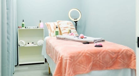 Relaxing massage room at Belle Lounge Spa, Saint George, GD, with soft peach tones and ambient lighting.