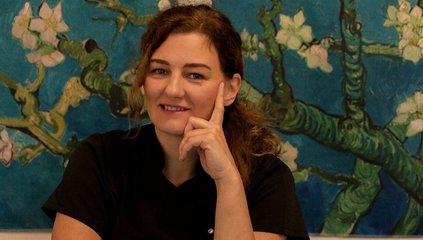 A practitioner at Healing Touch Therapies in Southampton, England, GB, smiling before a calming floral artwork.