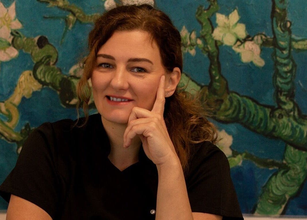 A practitioner at Healing Touch Therapies in Southampton, England, GB, smiling before a calming floral artwork.