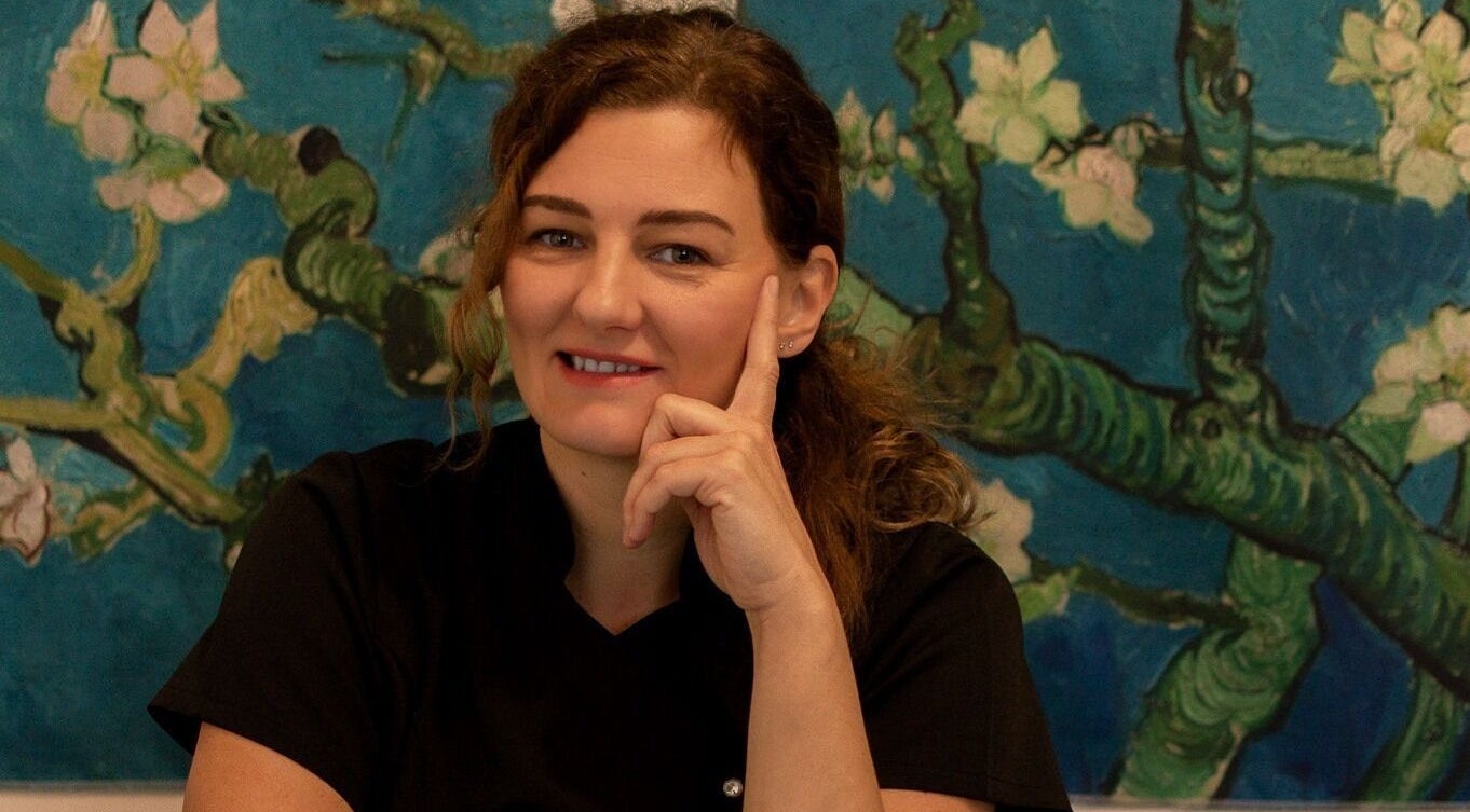 A practitioner at Healing Touch Therapies in Southampton, England, GB, smiling before a calming floral artwork.