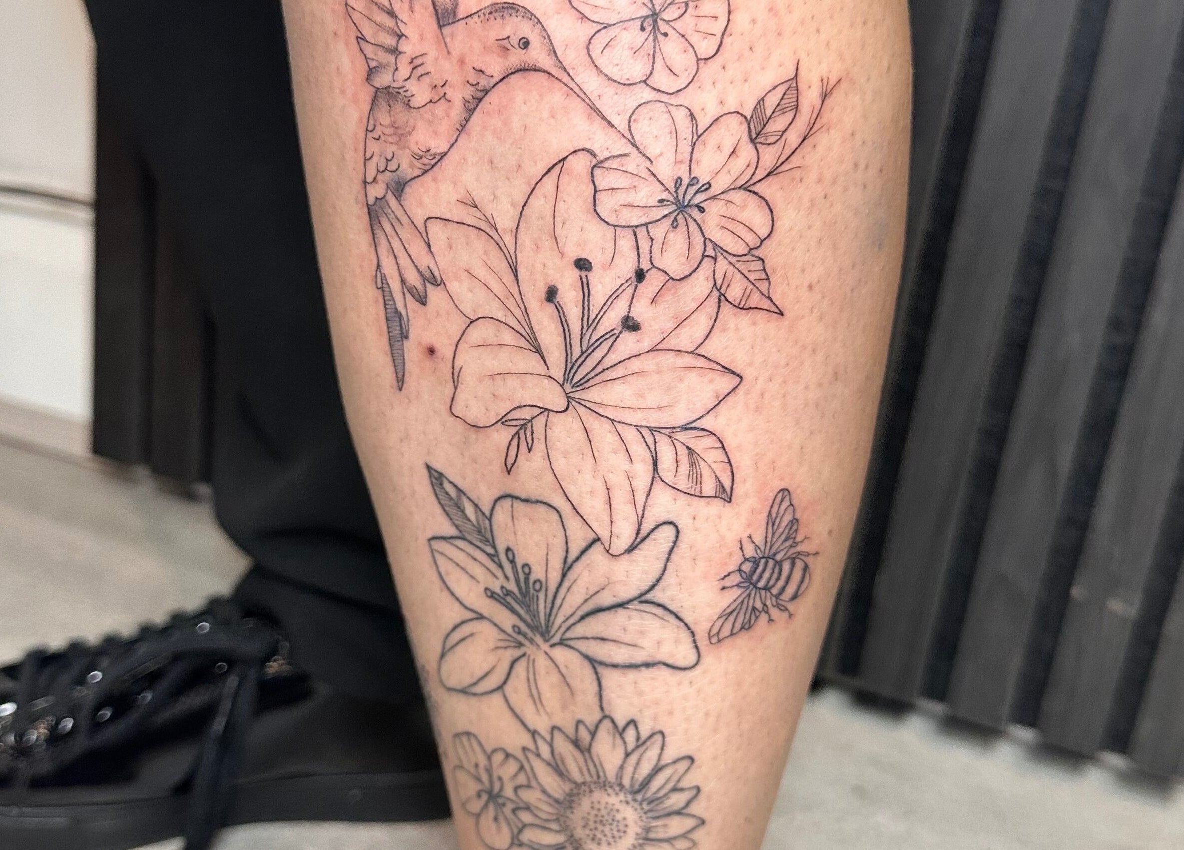 Detailed floral leg tattoo featuring hummingbird at Finelines by Fern Tattoo, Wickford, England, GB.