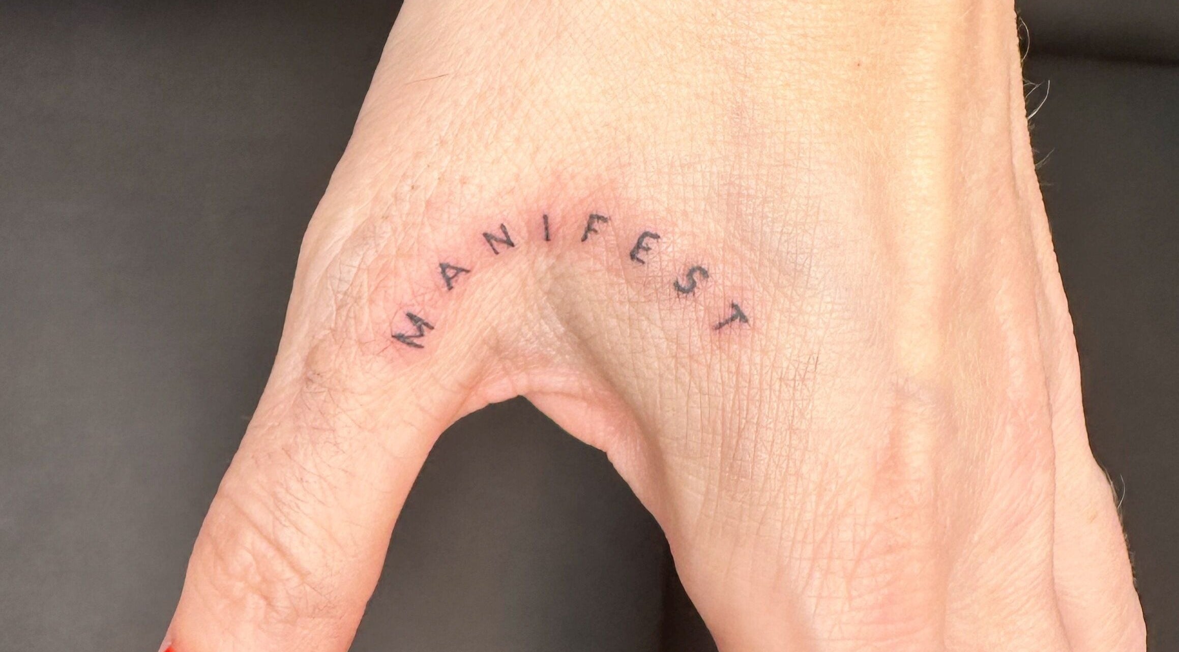 Finelines by Fern Tattoo in Wickford, England, GB showcases a minimalist 'Manifest' tattoo on a hand.