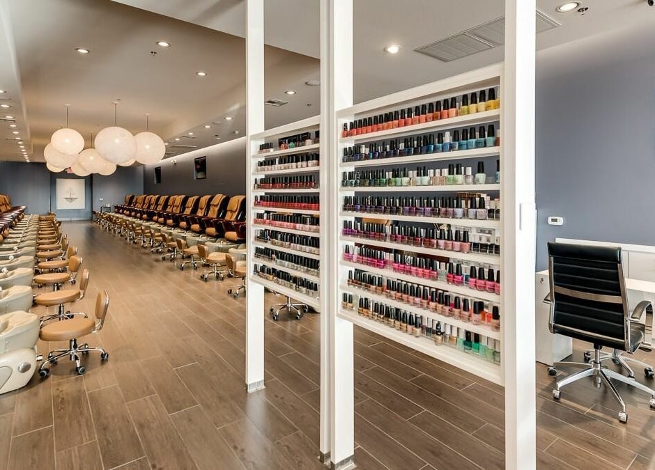 Sleek interior of Nail Lounge in Allen, Texas, US featuring rows of seating and colorful nail polish displays.