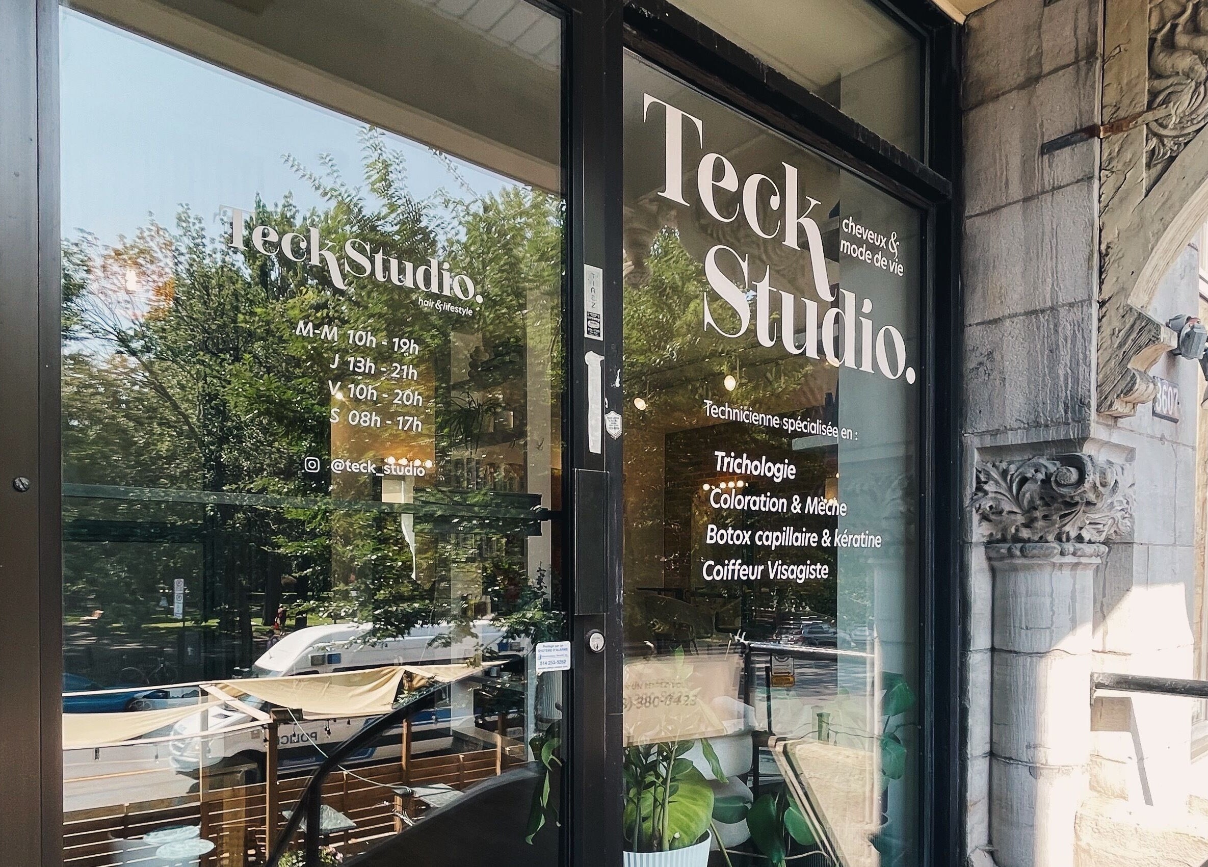 Entrée de Teck Studio à Montréal, Québec, CA, reflétant des arbres et affichant les horaires.