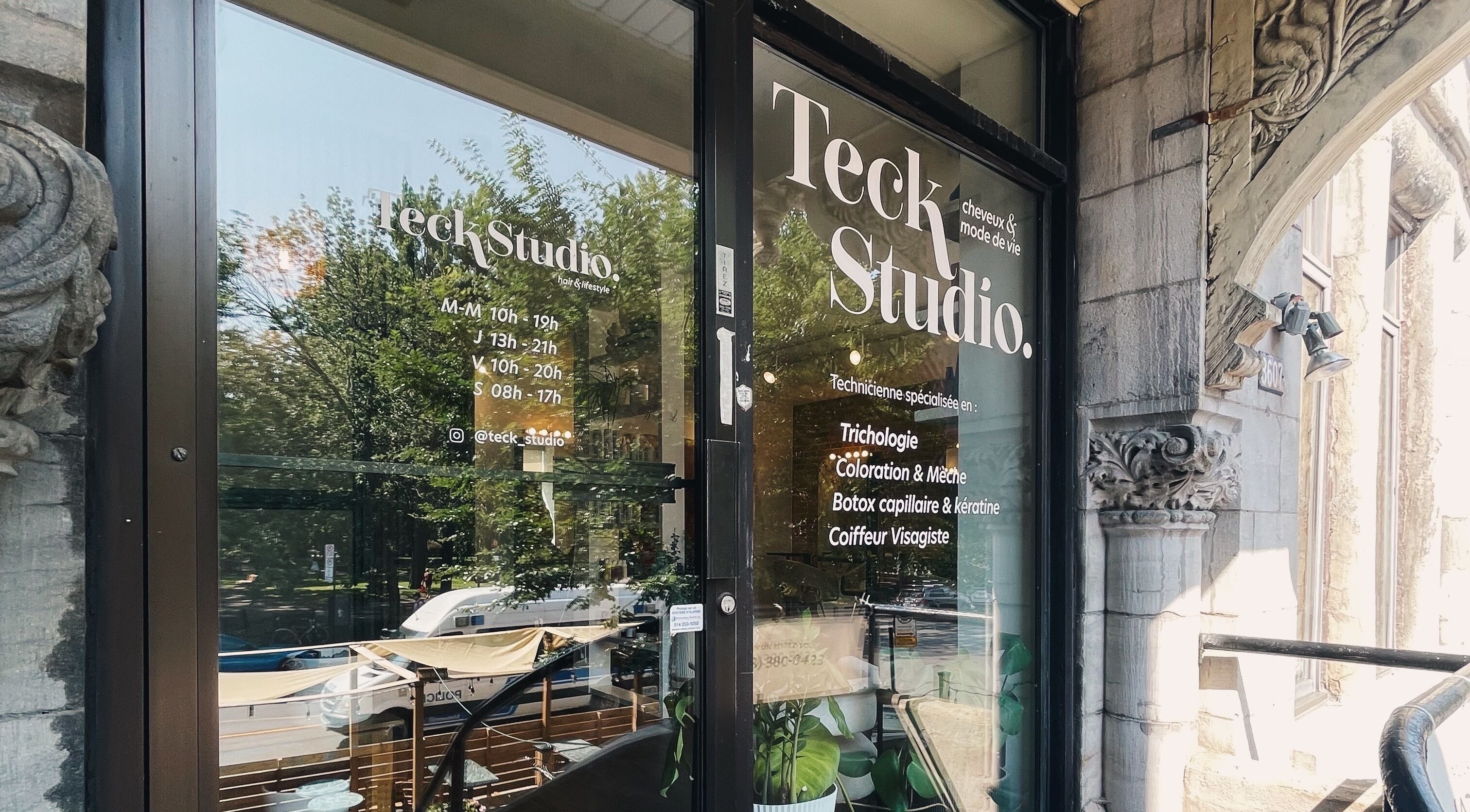 Entrée de Teck Studio à Montréal, Québec, CA, reflétant des arbres et affichant les horaires.