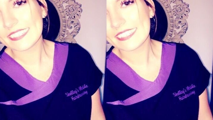 Smiling stylist at Hair By Shelley, Braintree, England, GB in branded uniform.