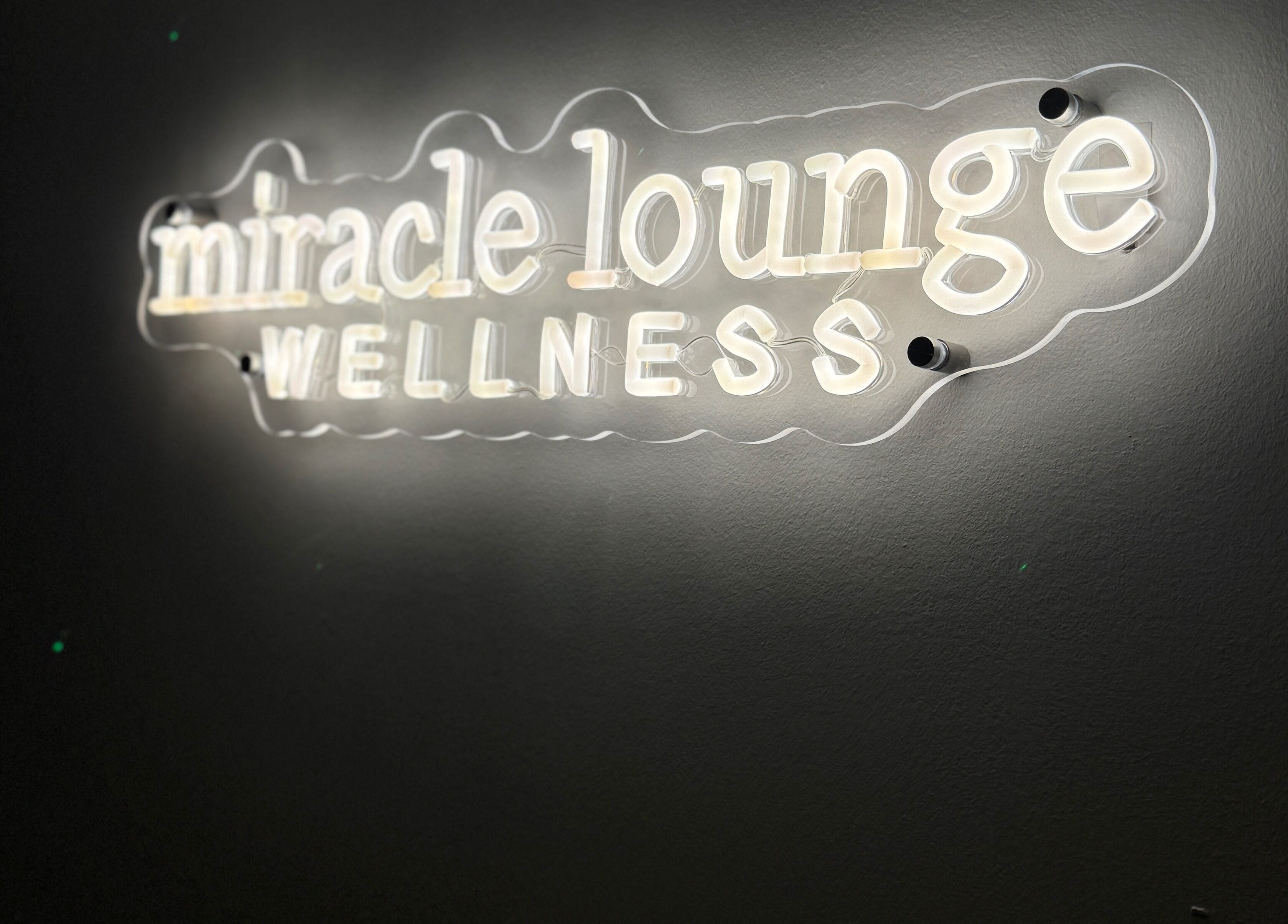 Illuminated 'Miracle Lounge' sign in Glasgow, Scotland, GB invites guests to a serene wellness experience.