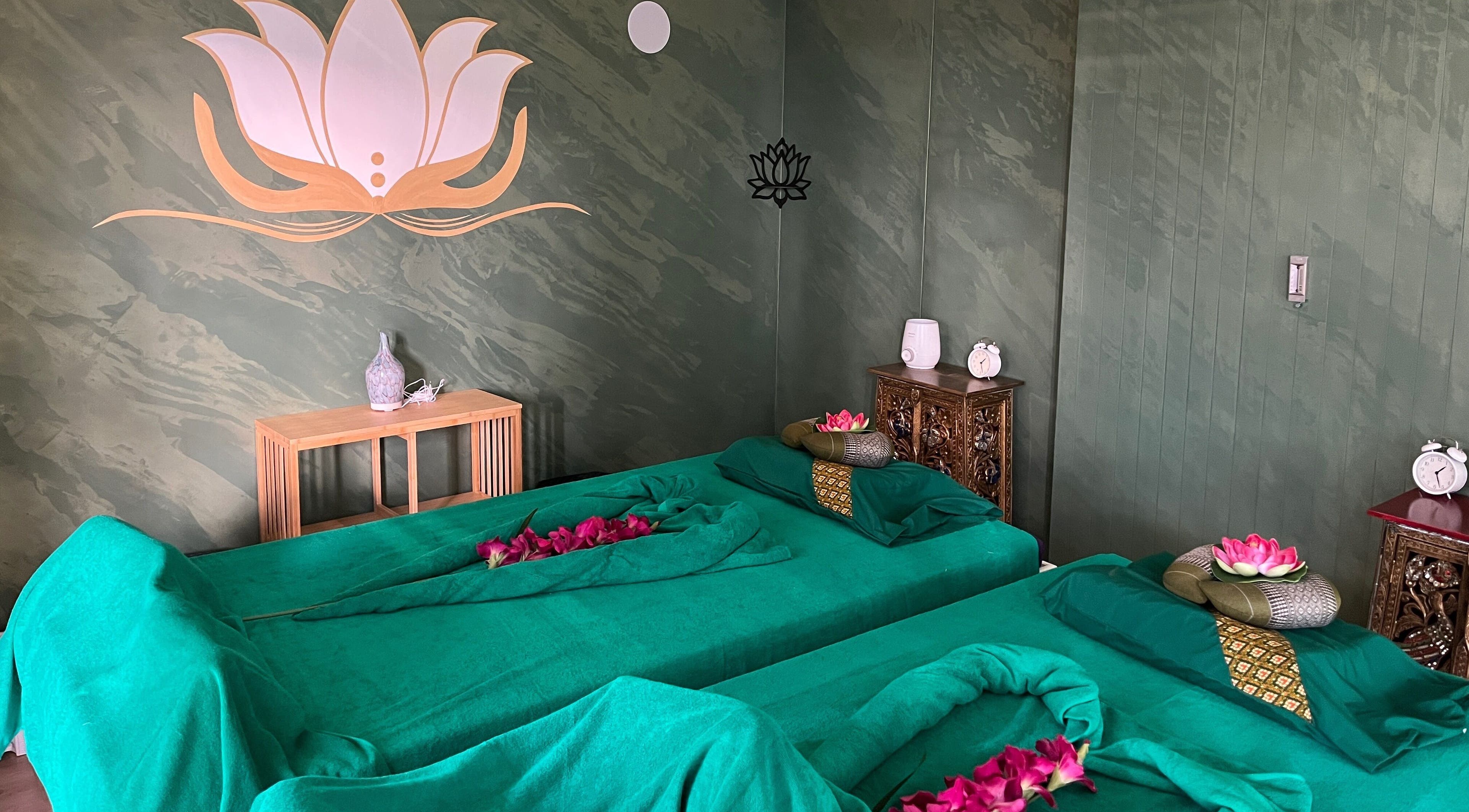 Camera massaggi elegante presso Locarno Siam Massage, Locarno, Ticino, CH, con letti verdi e decorazioni floreali.