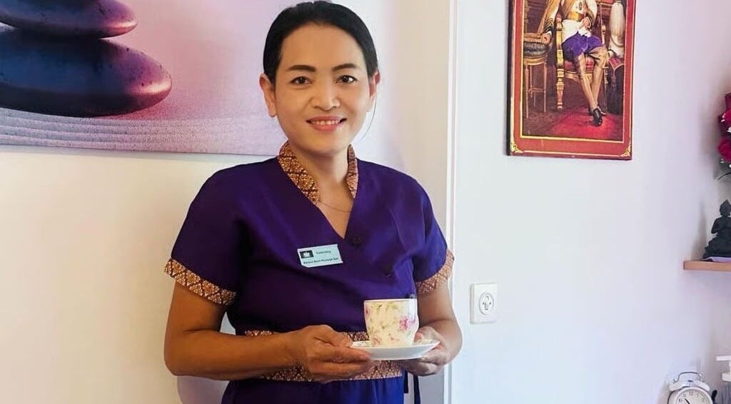 Terapeuta sorridente al Ascona Siam Massage Spa, Ascona, Ticino, CH, con tazza di tè in mano.