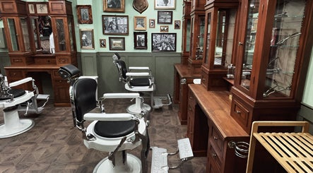 Interior retro al salonului Hair Hood 2 din Timișoara, Județul Timiș, RO, cu scaune de frizerie albe și lemn elegant.