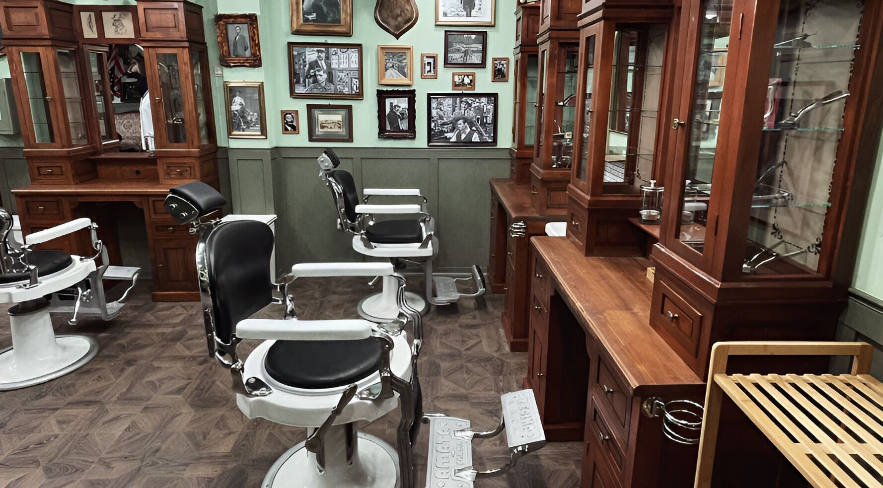 Interior retro al salonului Hair Hood 2 din Timișoara, Județul Timiș, RO, cu scaune de frizerie albe și lemn elegant.