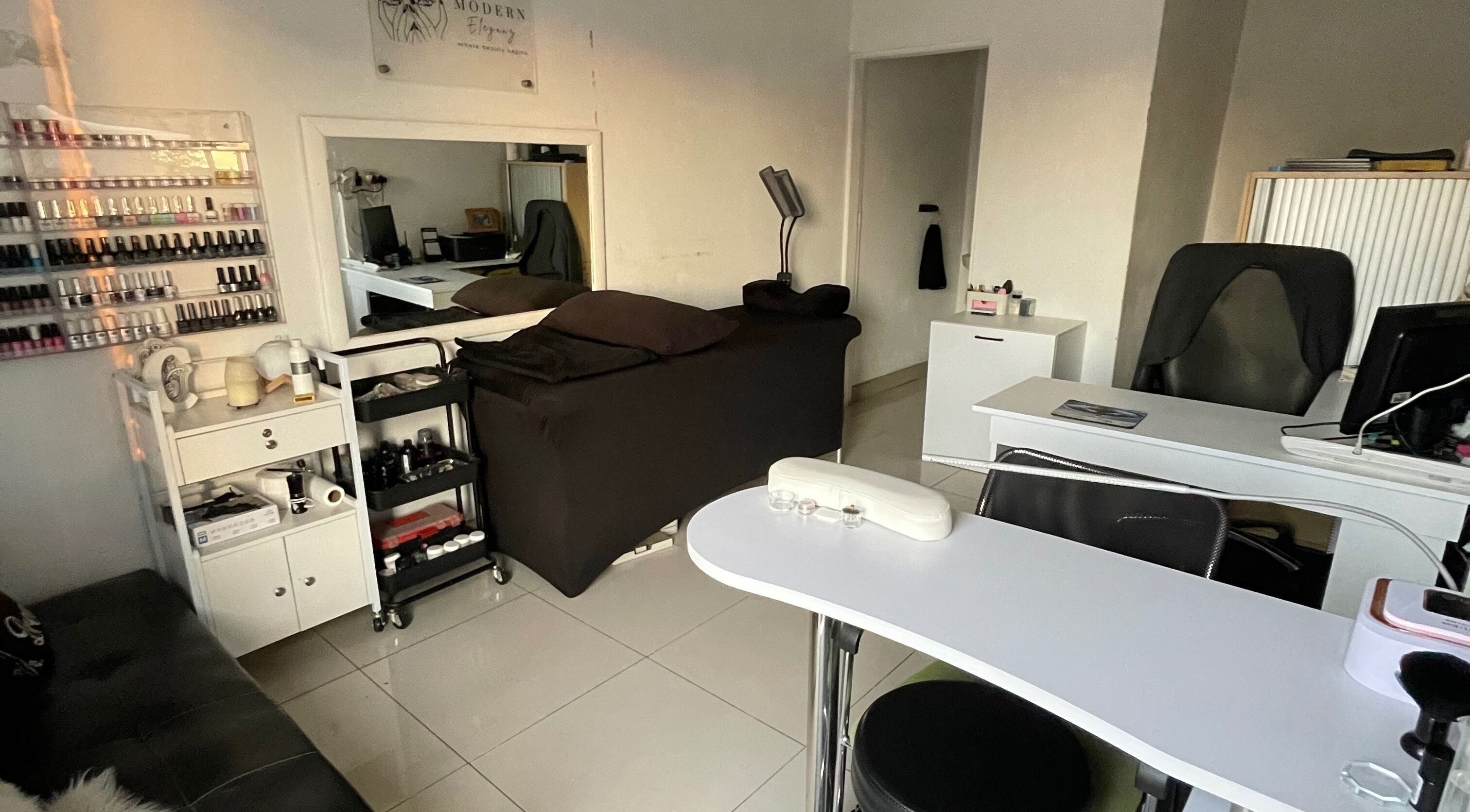 Elegant nail salon interior at Modern Eleganz, Soweto, Gauteng, ZA with sleek furnishings and polish display.