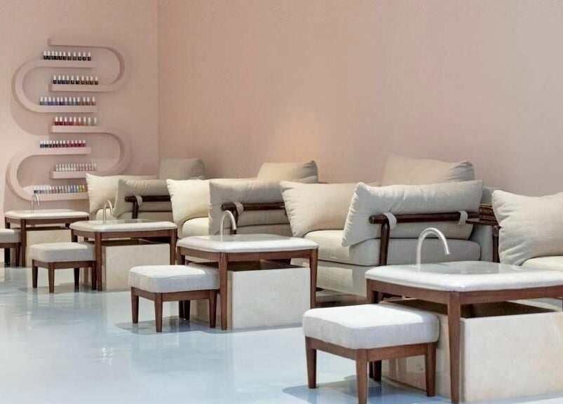 Elegant seating area at Mend Salon in Riyadh, Riyadh Province, SA, featuring cozy cushions and nail polish shelves.