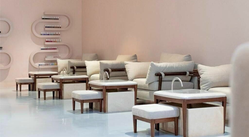 Elegant seating area at Mend Salon in Riyadh, Riyadh Province, SA, featuring cozy cushions and nail polish shelves.