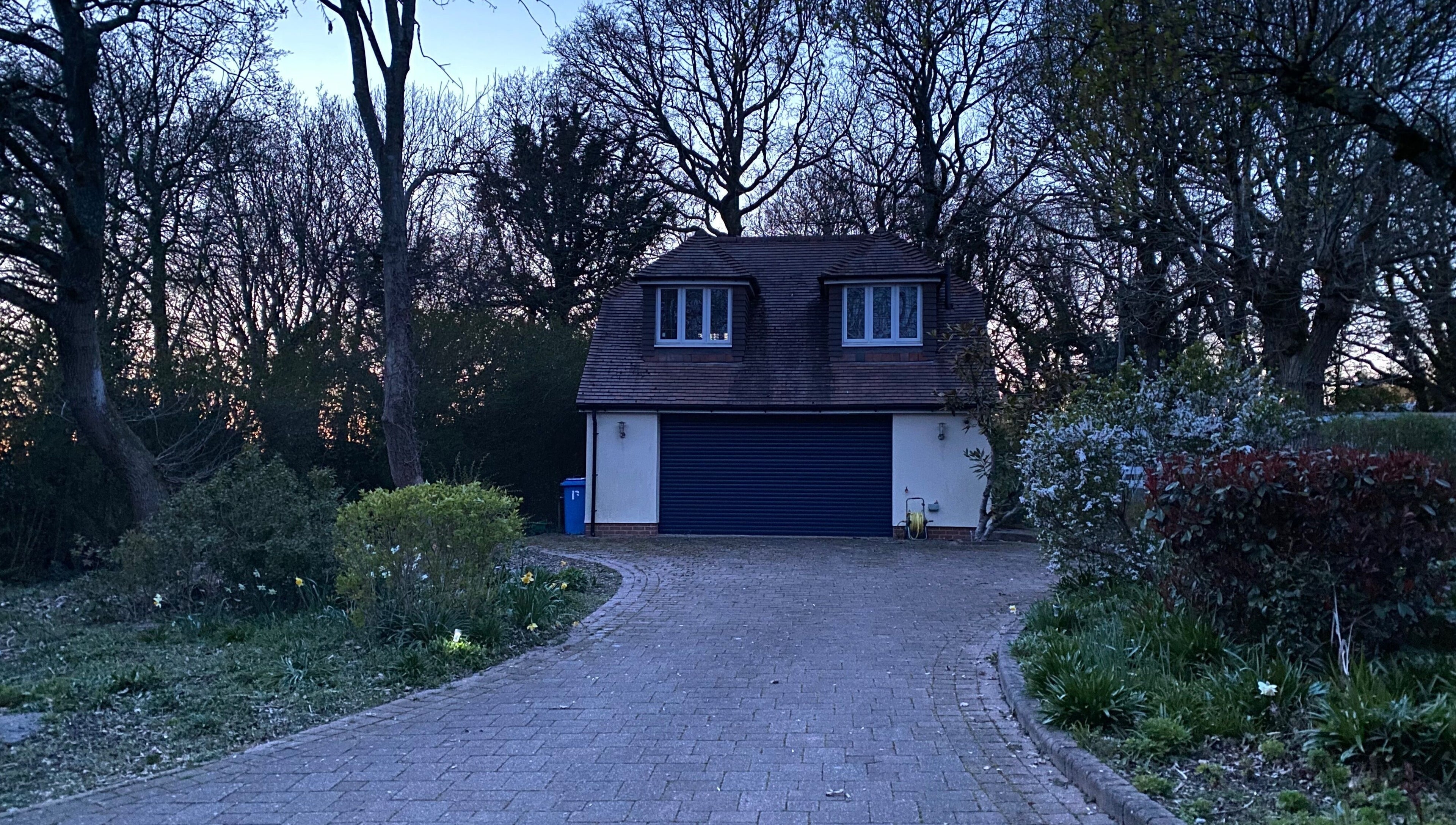 Quiet, serene entrance of Worthing Clinic with Nurse Rebecca at dusk, surrounded by trees in Worthing, England, GB.