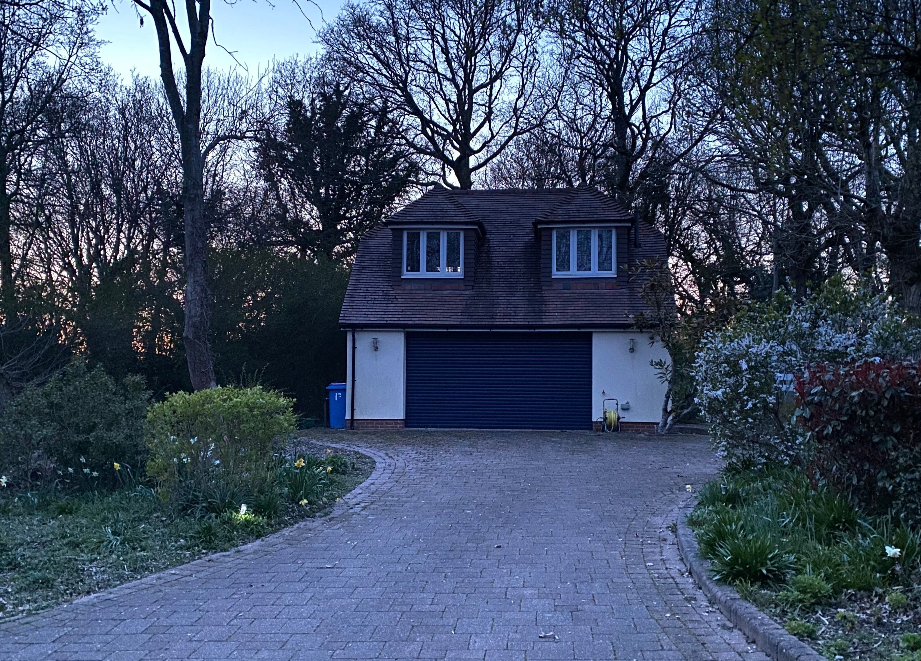 Quiet, serene entrance of Worthing Clinic with Nurse Rebecca at dusk, surrounded by trees in Worthing, England, GB.