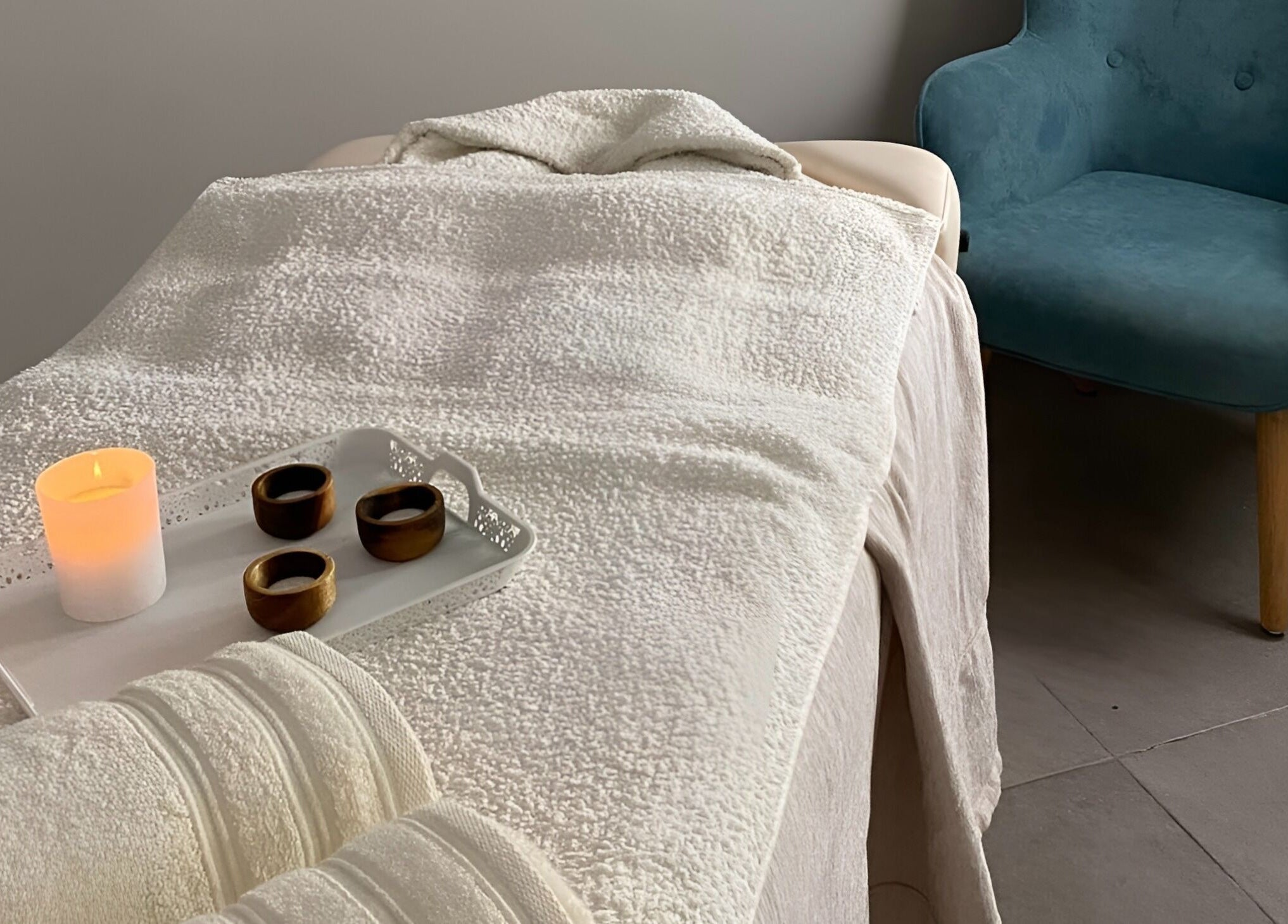 Serene massage room at The Cutting Room, Mandria, Paphos, CY with a candlelit ambiance and cozy chair.