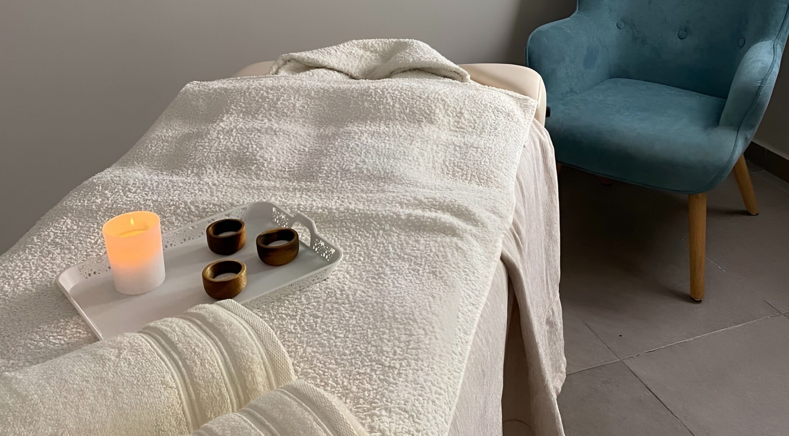 Serene massage room at The Cutting Room, Mandria, Paphos, CY with a candlelit ambiance and cozy chair.