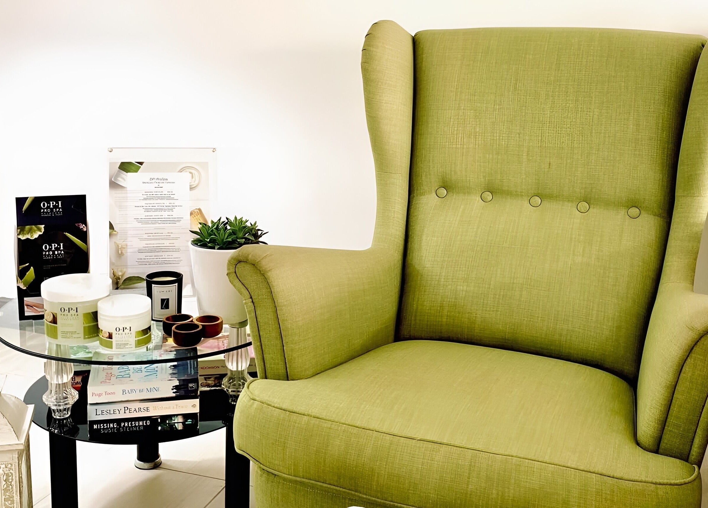 Relaxing green chair in The Cutting Room, Mandria, Paphos, CY, next to a table with beauty products.