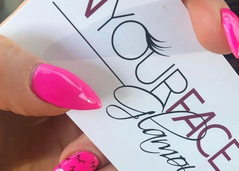A vibrant pink manicure holding In Your Face Glamour card in Edmonton, Alberta, CA.