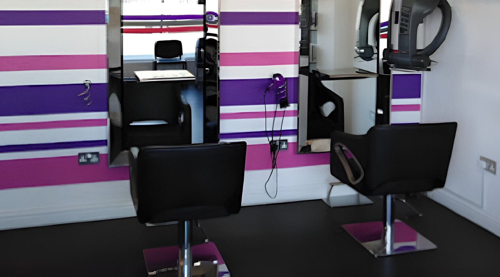 Modern salon chairs at SeventyFour Hair, featuring bold pink and purple decor, Farnborough, England, GB.