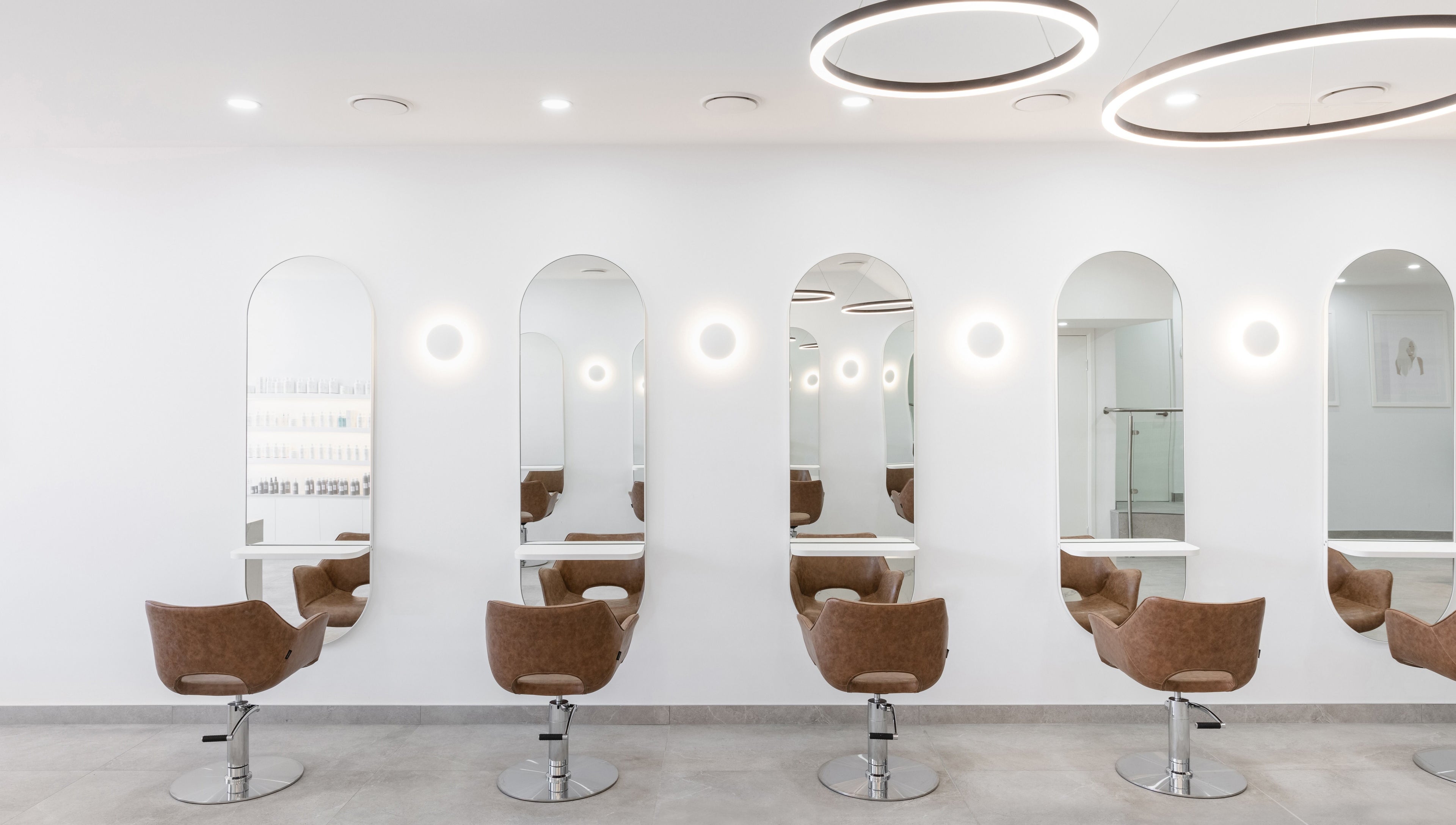 Chic salon styling stations at Mane Painters in Kingsgrove, NSW, AU with modern mirrors and plush chairs.