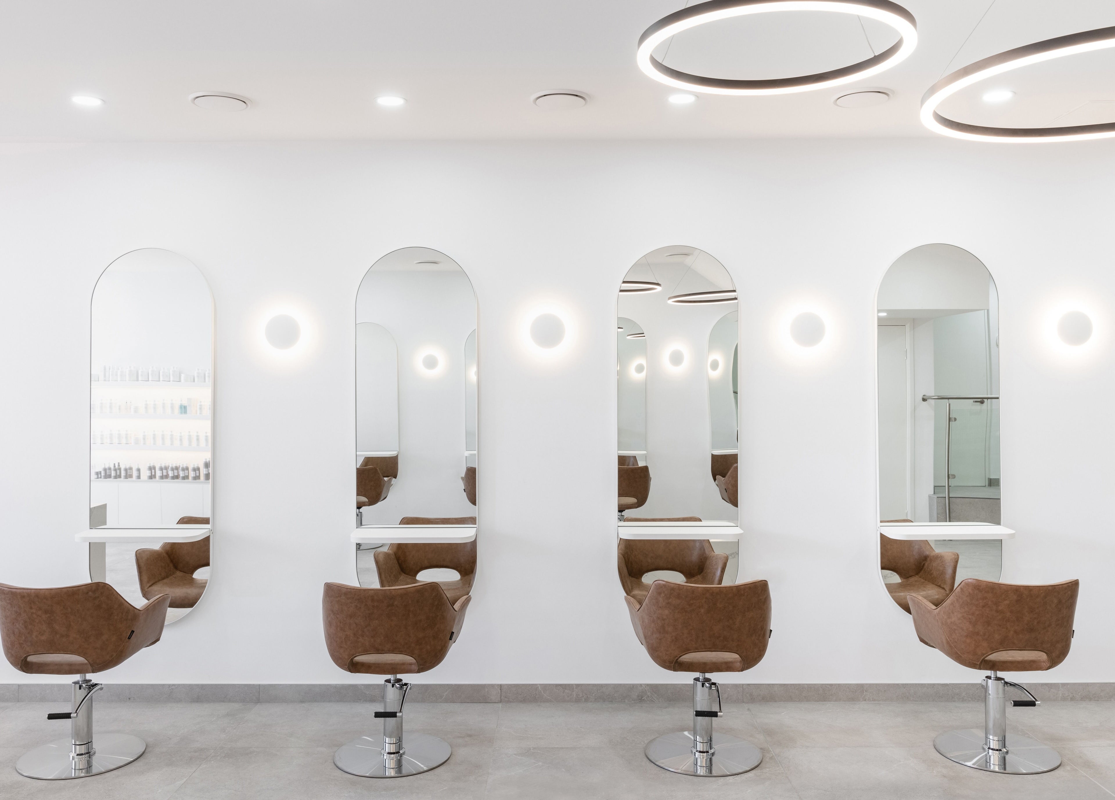 Chic salon styling stations at Mane Painters in Kingsgrove, NSW, AU with modern mirrors and plush chairs.