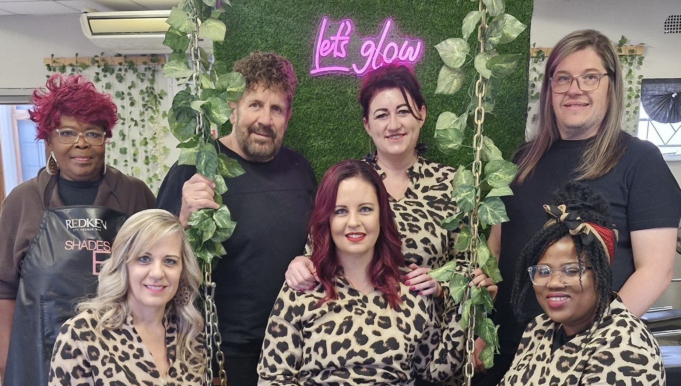 Team of stylists at Xquisite Nails, Bloemfontein, Free State, ZA, in front of a 'Let's Glow' sign.
