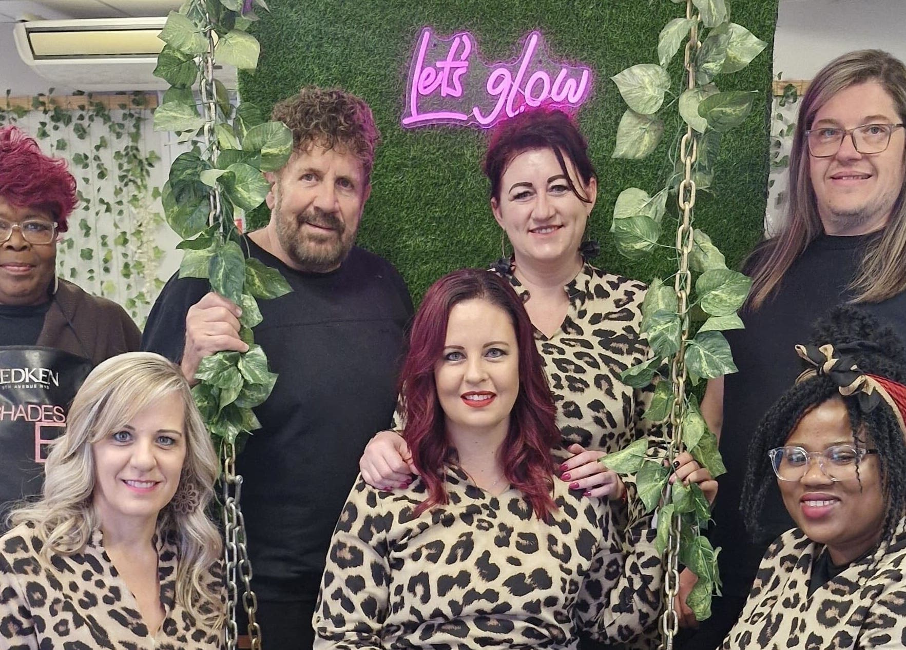 Team of stylists at Xquisite Nails, Bloemfontein, Free State, ZA, in front of a 'Let's Glow' sign.