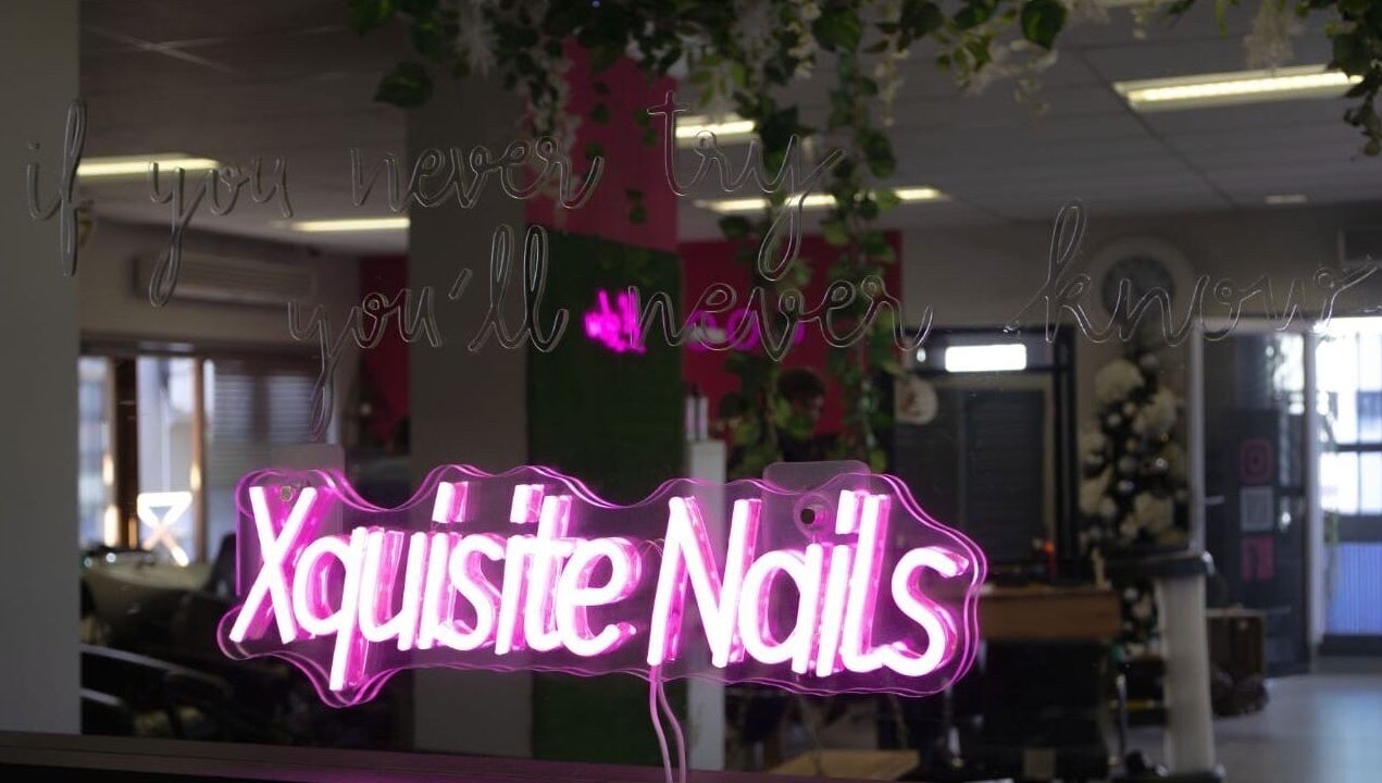 Vibrant neon sign reading 'Xquisite Nails' inside the Bloemfontein salon in Free State, ZA.