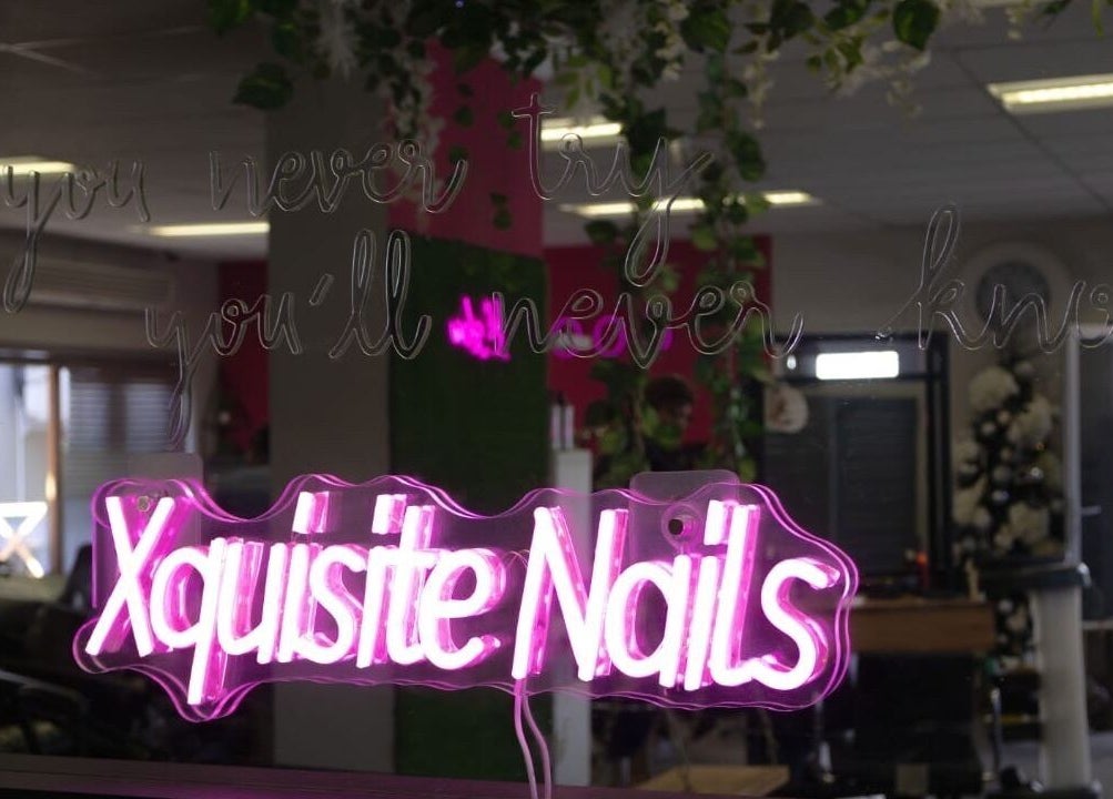 Vibrant neon sign reading 'Xquisite Nails' inside the Bloemfontein salon in Free State, ZA.