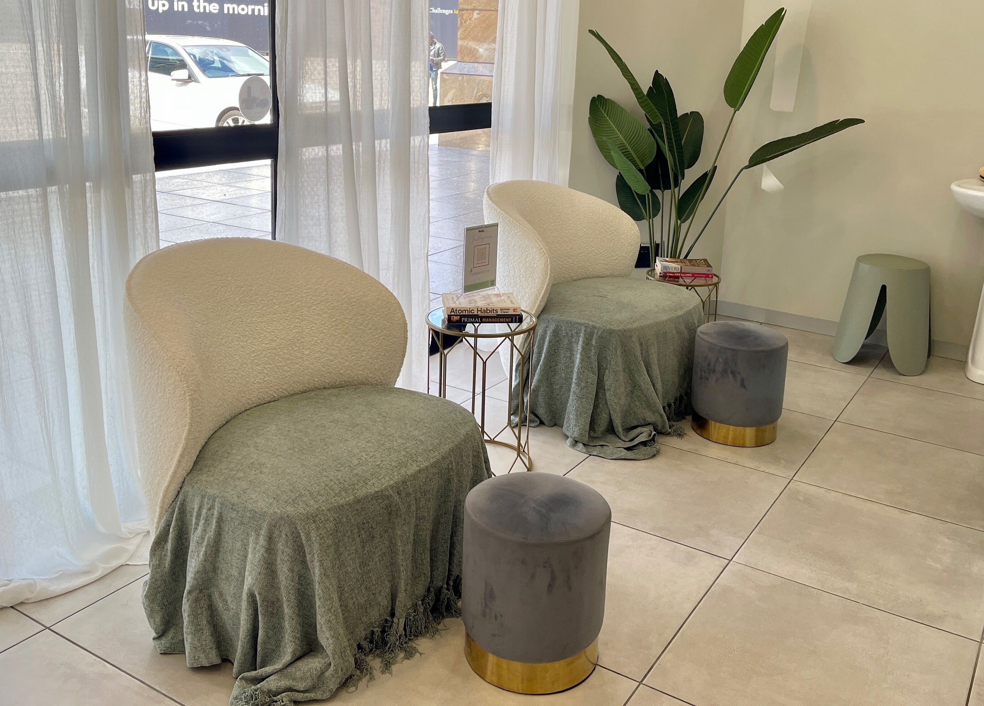 Cozy lounge area at KimCo Beauty Lab, Sandton, Gauteng, ZA with plush chairs and a potted plant.