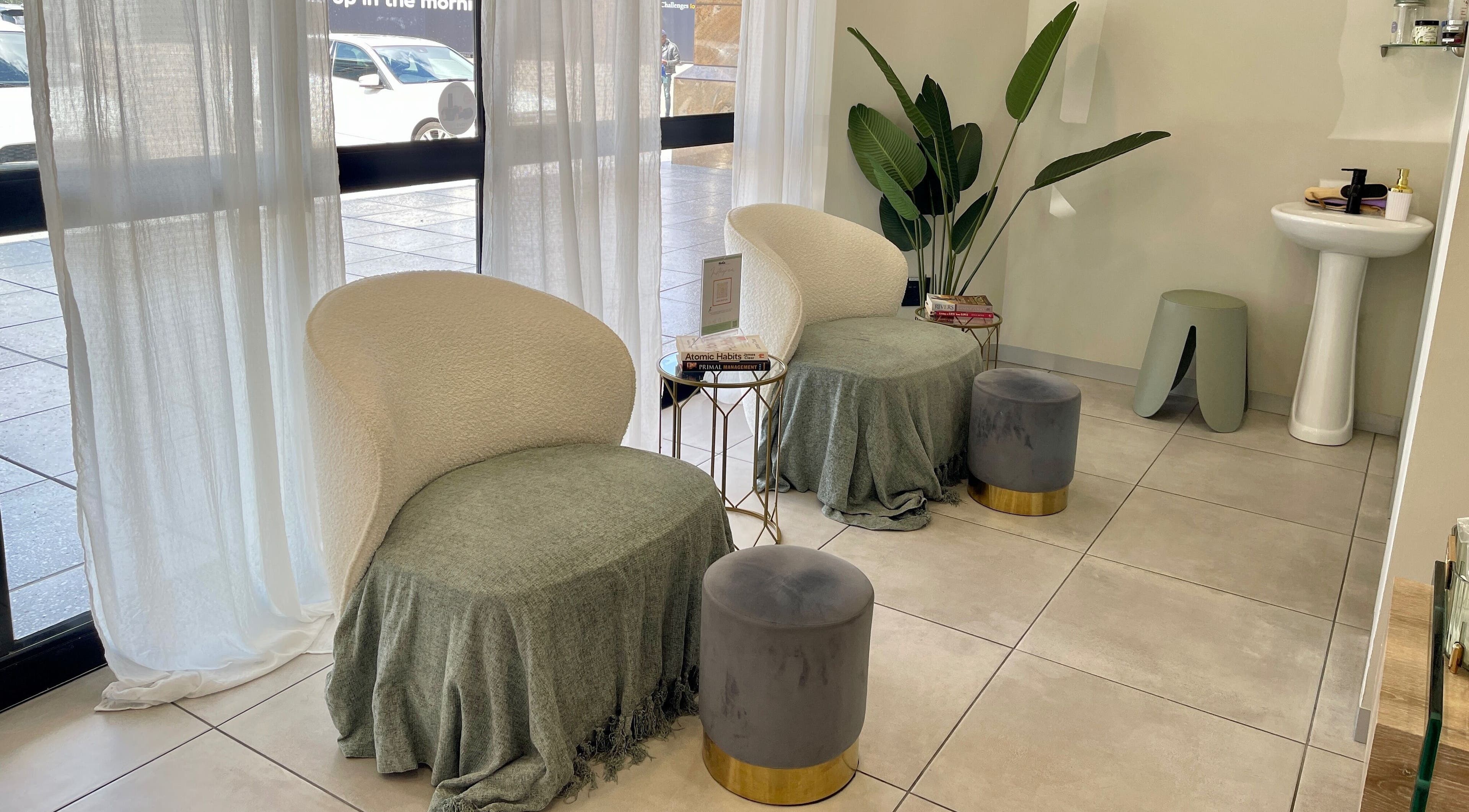 Cozy lounge area at KimCo Beauty Lab, Sandton, Gauteng, ZA with plush chairs and a potted plant.