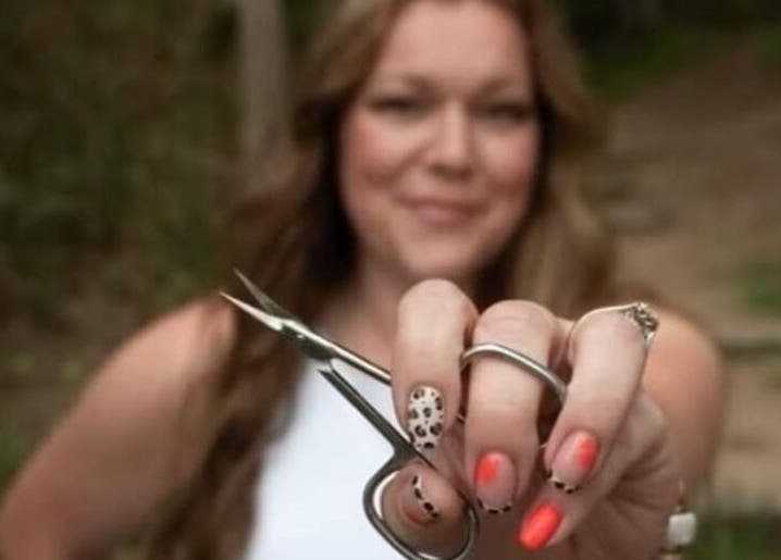 Woman showcasing vibrant nail art with scissors at Hardcorr Nails in Zimmerman, Minnesota, US.