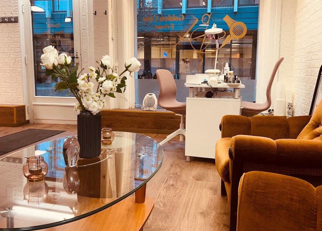 Koselig interiør på Golden Cuts Frisør Sarpsborg, Østfold, NO med sofa, blomster og salongbord.