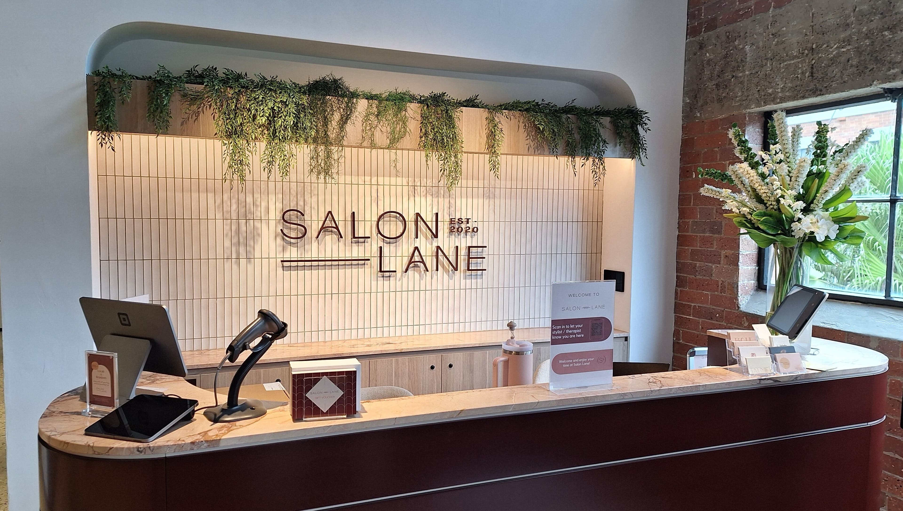 Modern reception desk at Reset With Khloe, West End, Queensland, AU adorned with greenery and sleek design.