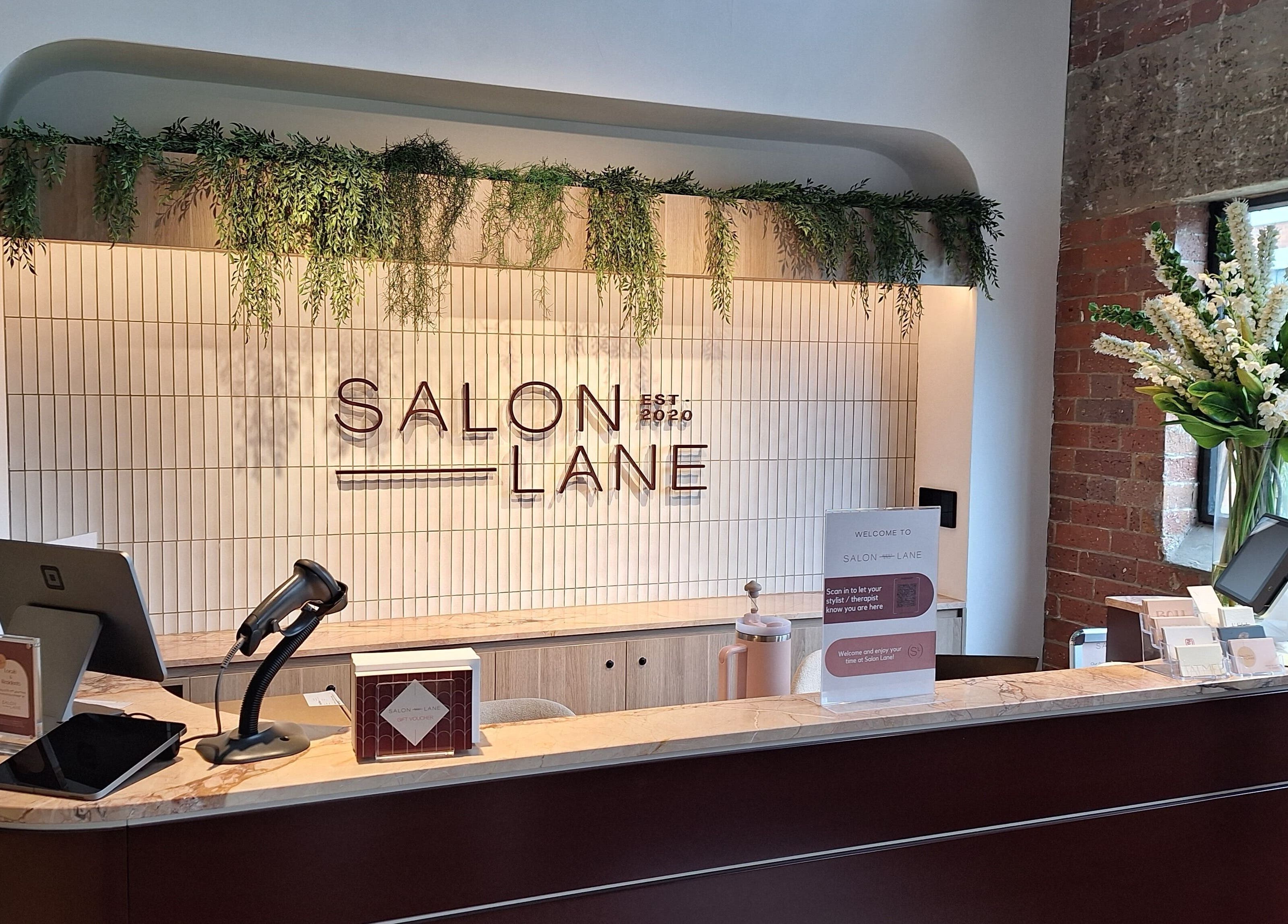 Modern reception desk at Reset With Khloe, West End, Queensland, AU adorned with greenery and sleek design.