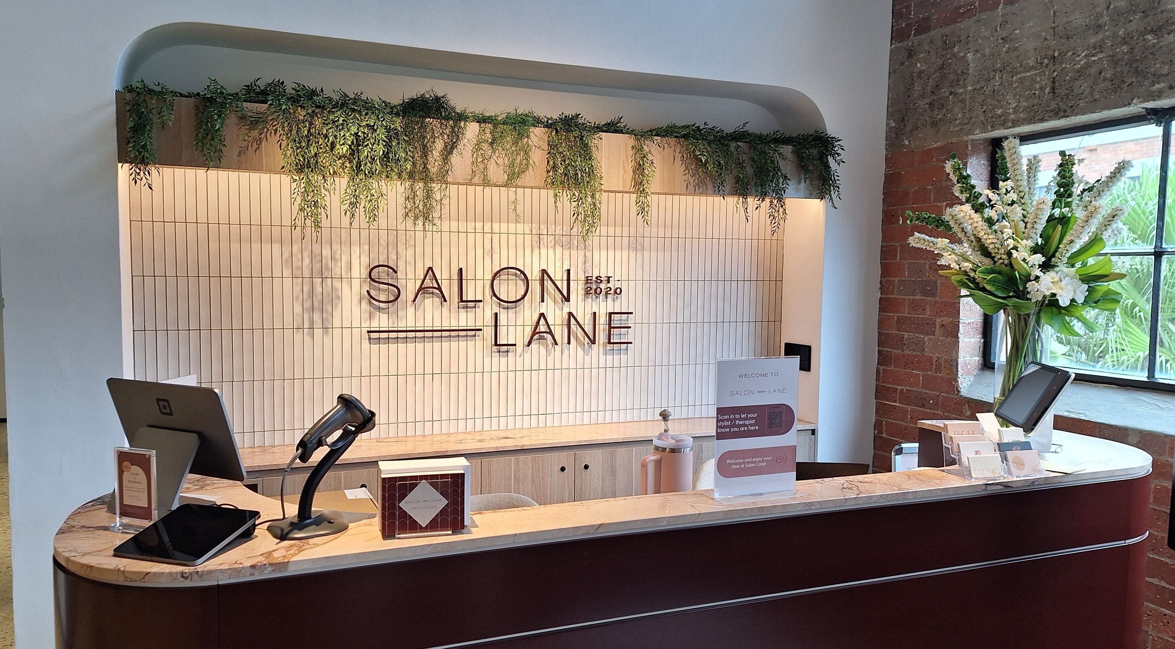Modern reception desk at Reset With Khloe, West End, Queensland, AU adorned with greenery and sleek design.