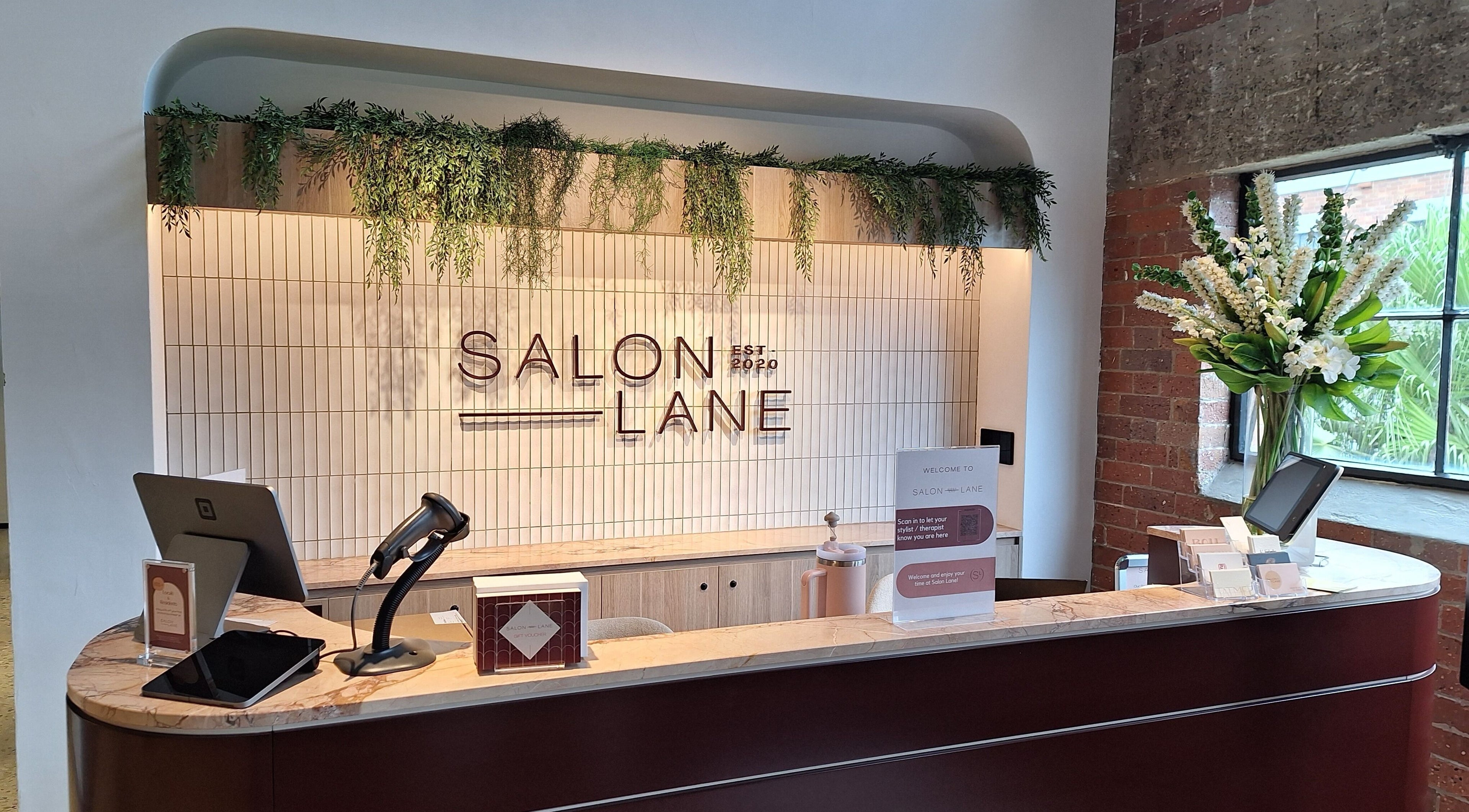 Modern reception desk at Reset With Khloe, West End, Queensland, AU adorned with greenery and sleek design.